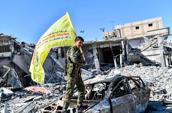 جندى يحمل علم سوريا الديمقراطية فى مدينة الرقة عقب تحريرها
