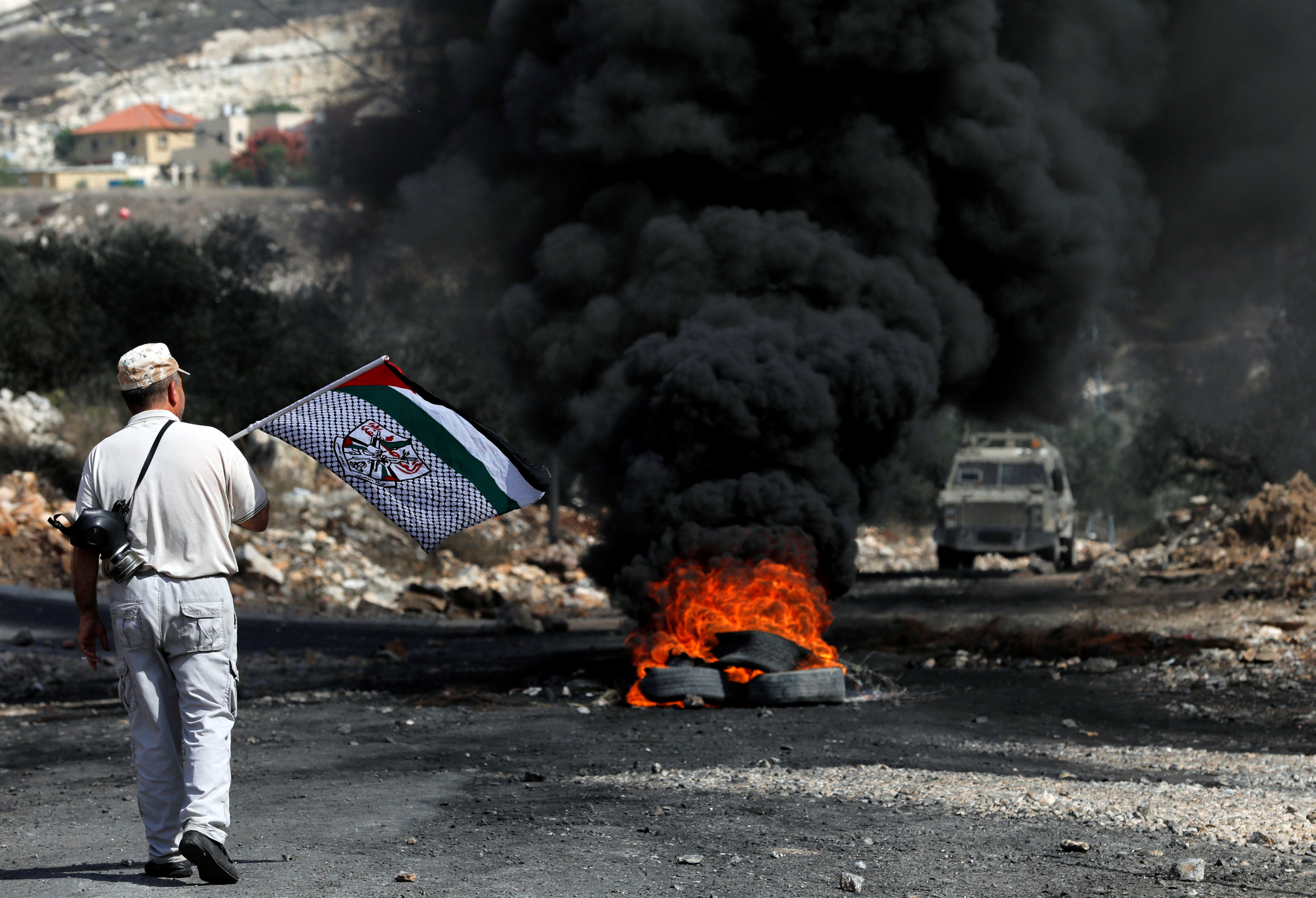 رجل فلسطينى يرفع علم بلاده فى مواجه قوات الاحتلال الإسرائيلى