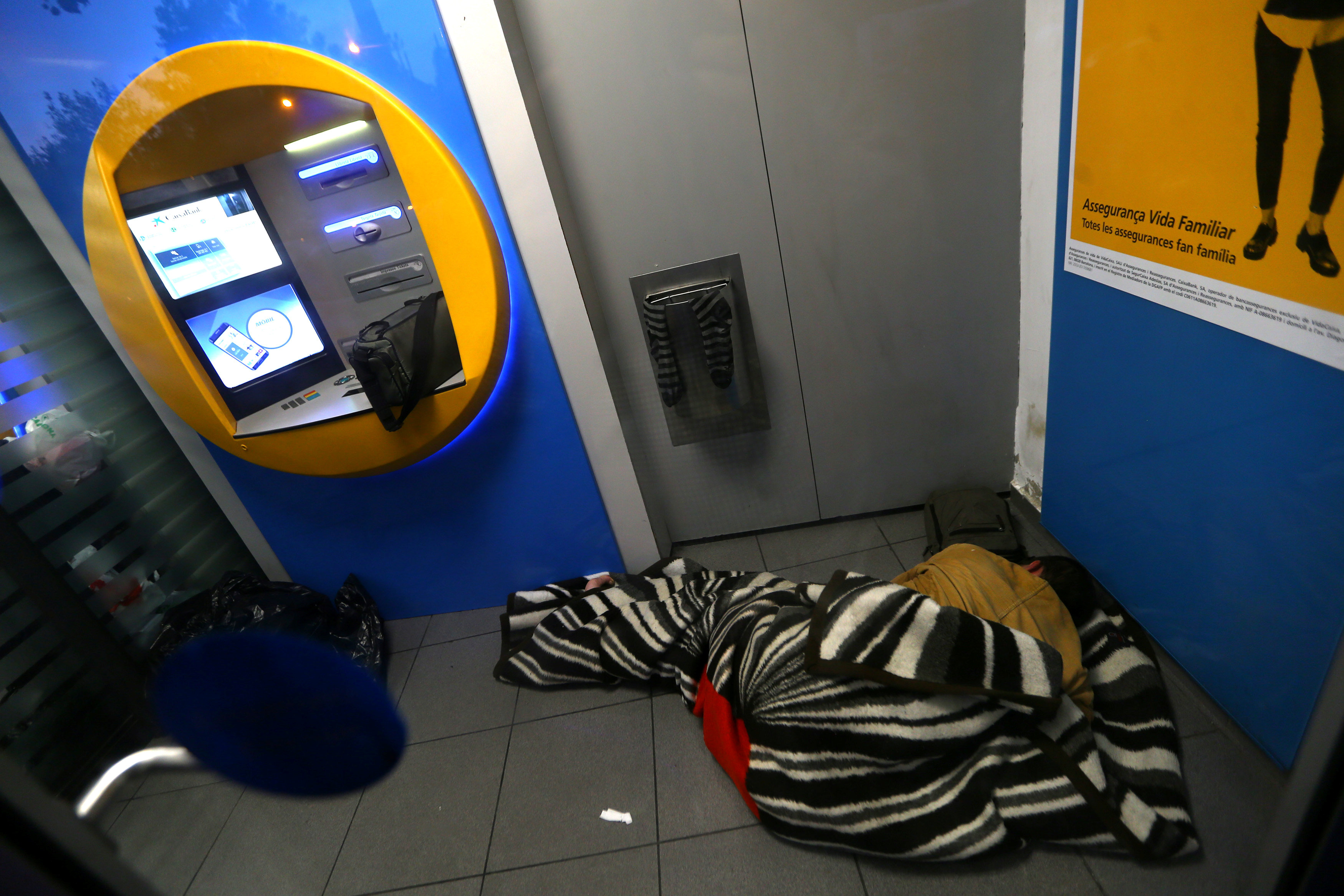 رجل ينام أمام ماكينة صراف آلى ضمن حملة لتأييد استقلال كتالونيا