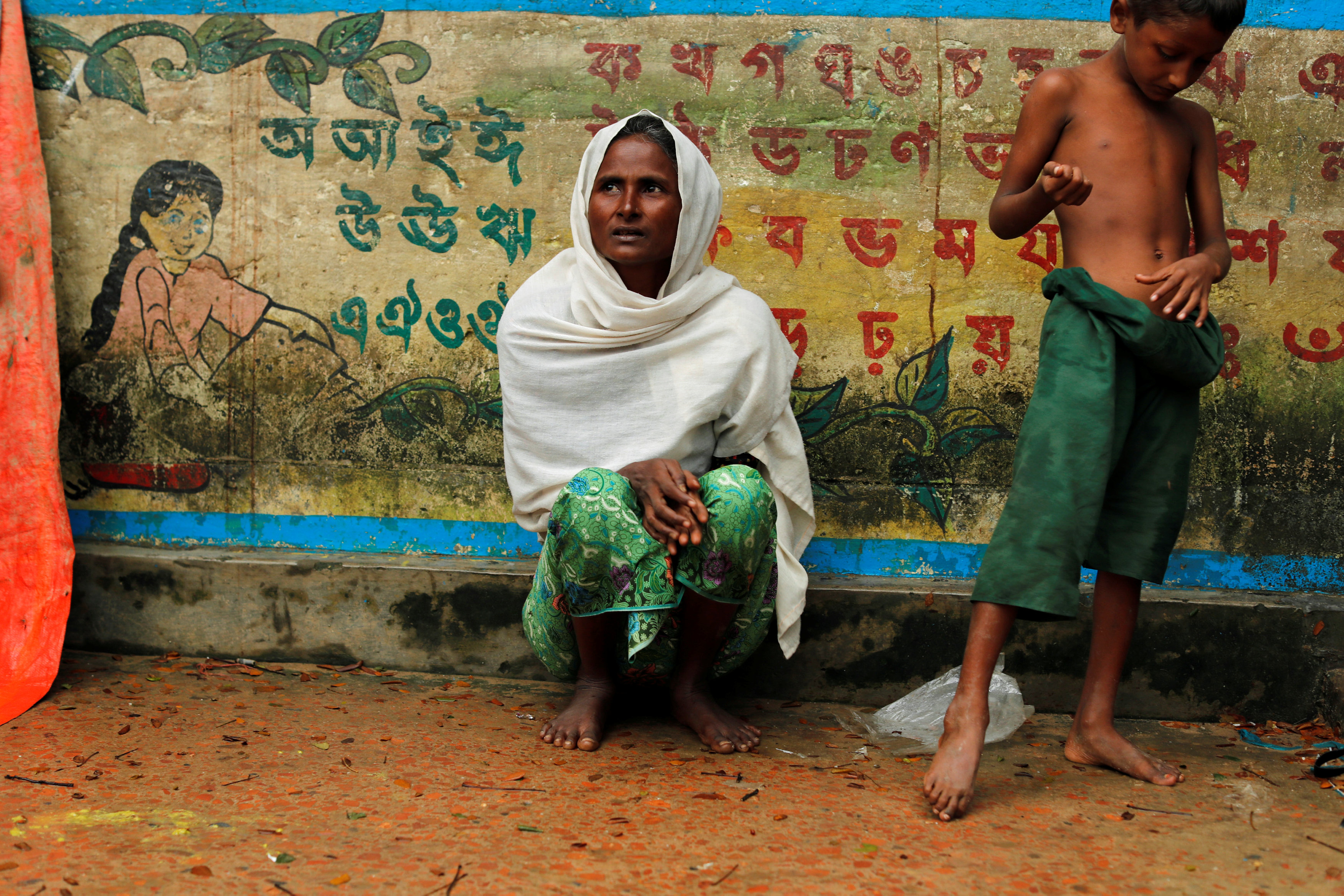 طفل من الروهينجا يلعب بجوار والدته فى المخيمات ببنجلادش
