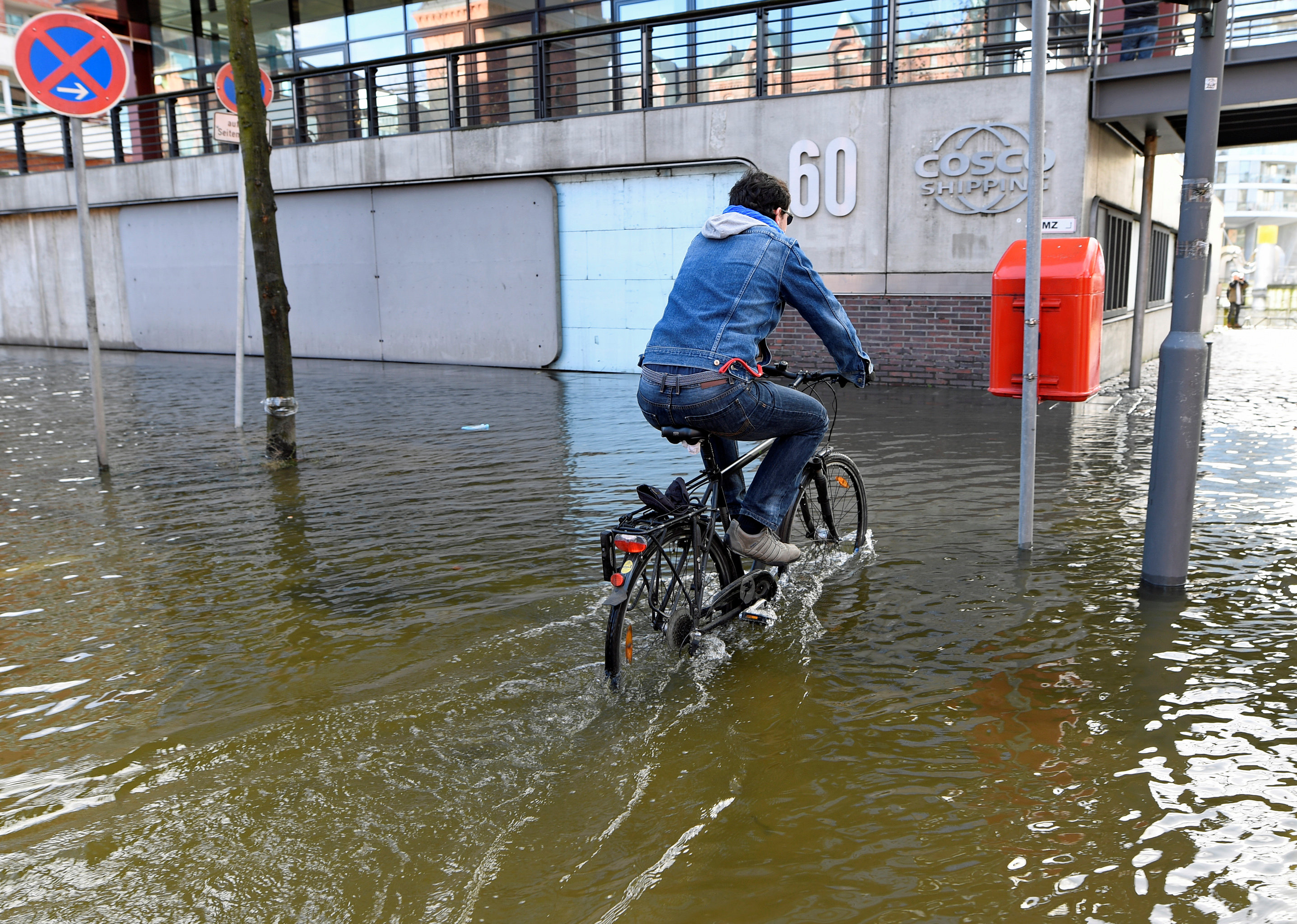 شاب يستخدم دراجته للتنقل وسط مياه الأمطار