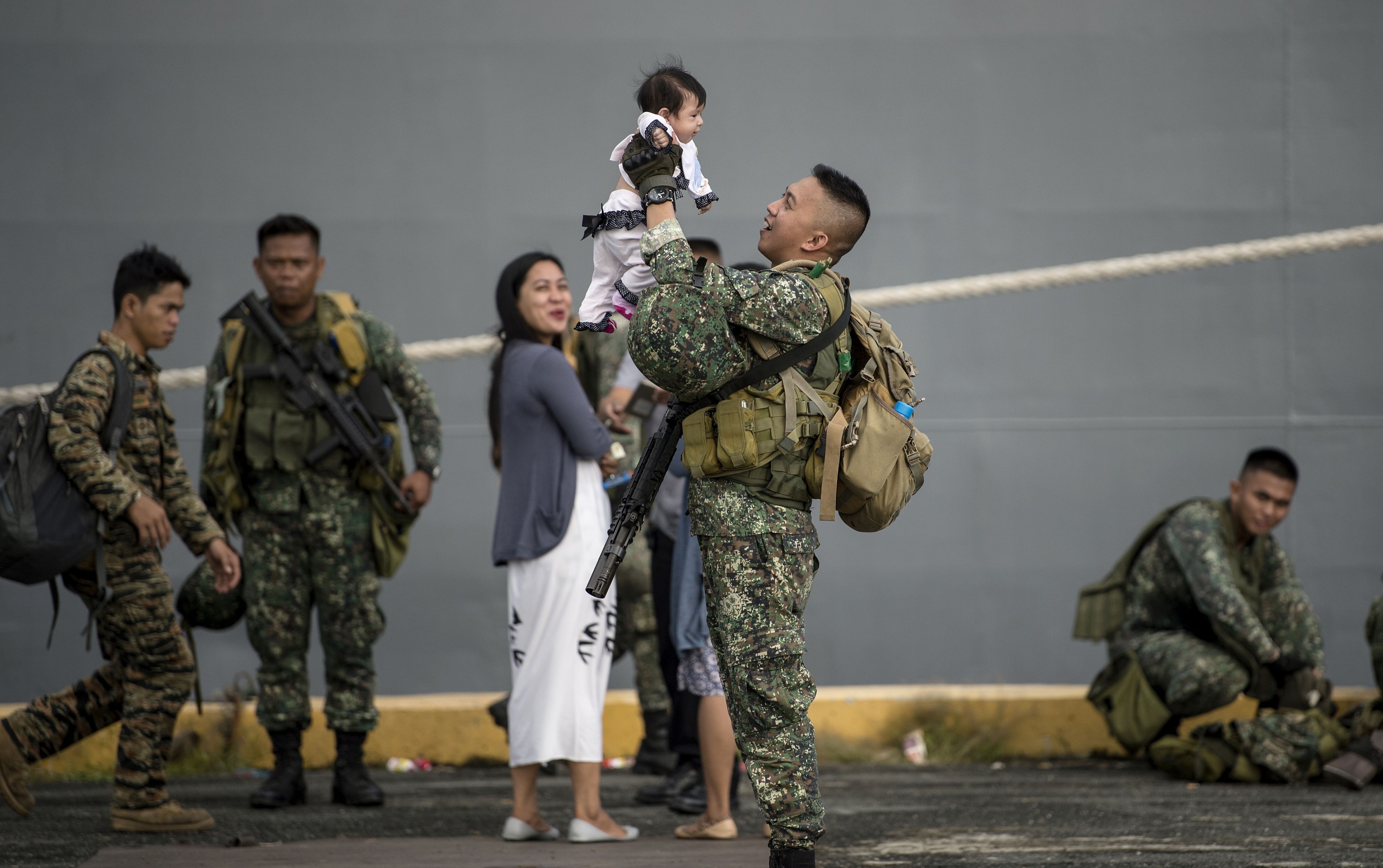 أحد أفراد الجيش يحمل طفله الرضيع لدى وصوله ميناء مانيلا