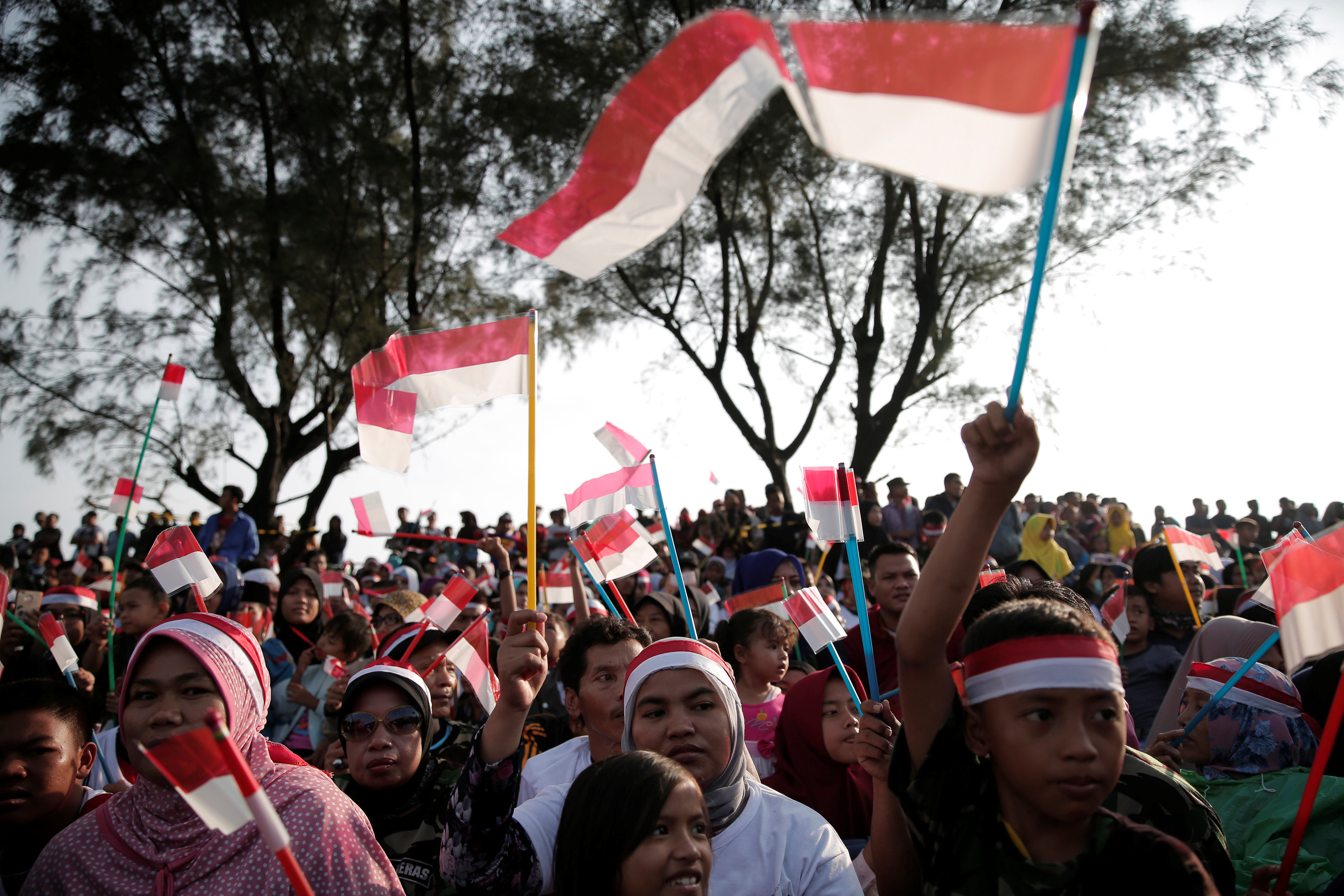 مواطنون يحملون الأعلام أثناء مشاهدة العرض العسكرى للجيش الإندونيسى