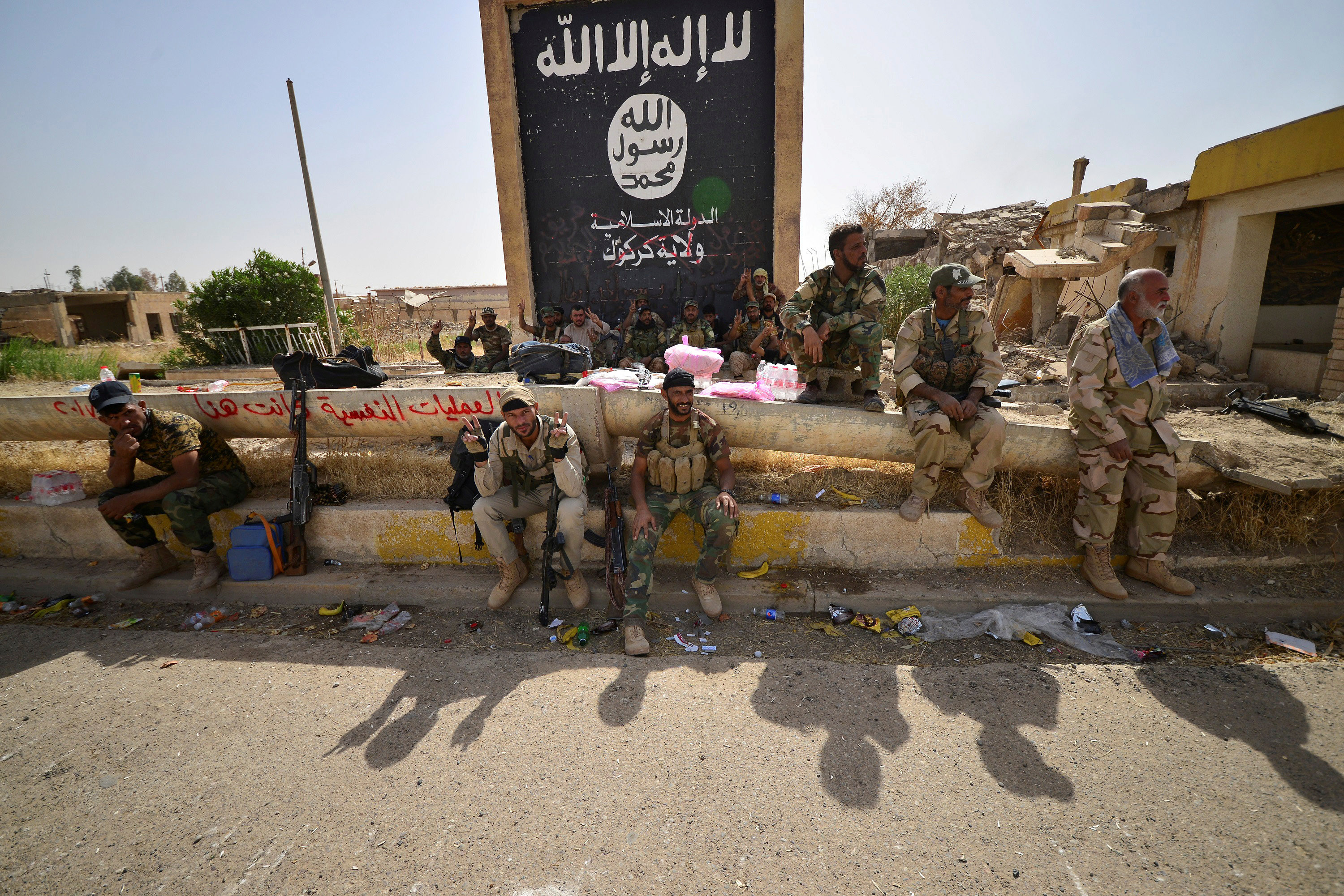 القوات العراقية تجلس أمام لافتة للتنظيم الإرهابى فى الحويجة