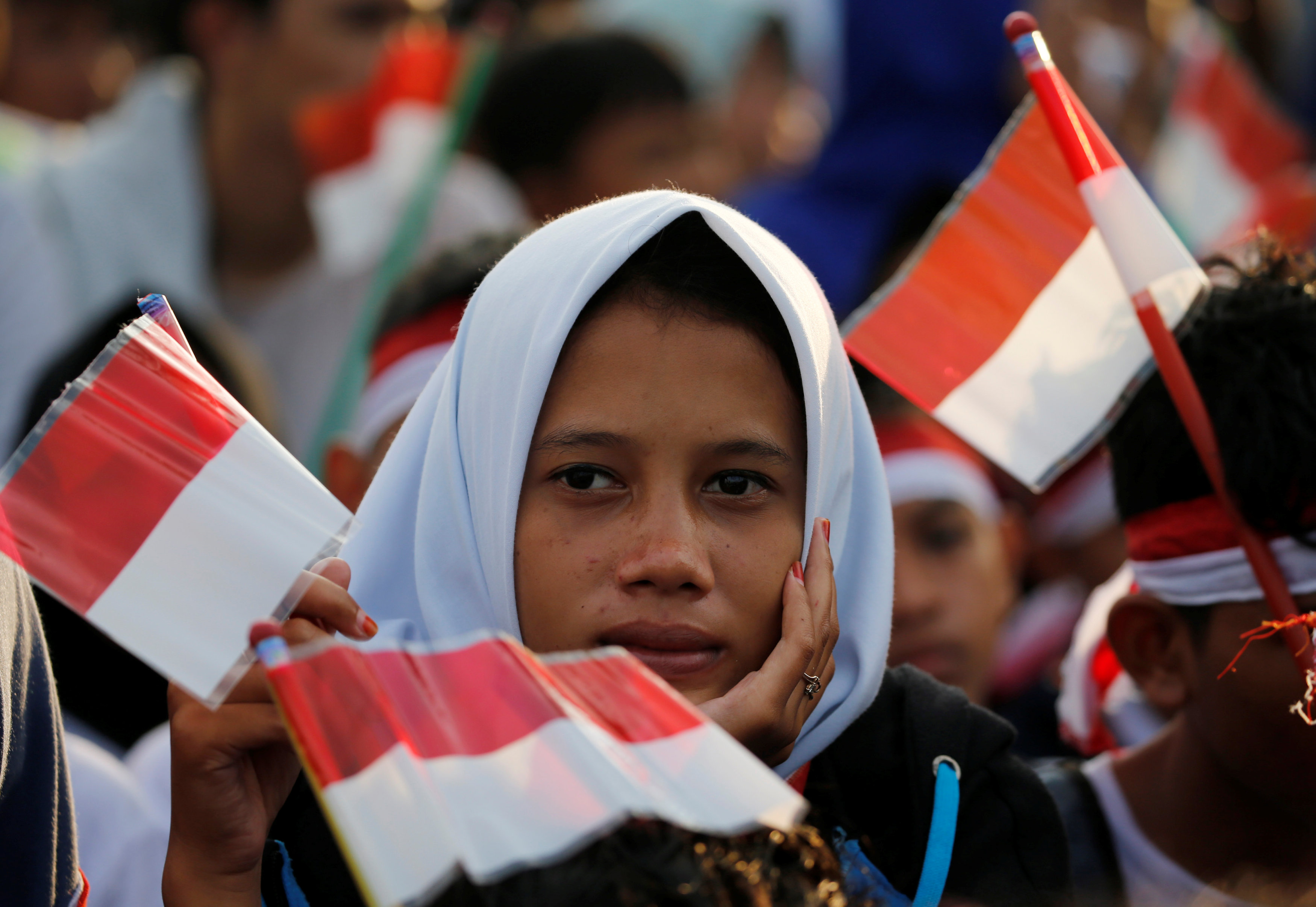 فتاة تحمل علم إندونيسيا خلال متابعتها العرض العسكرى