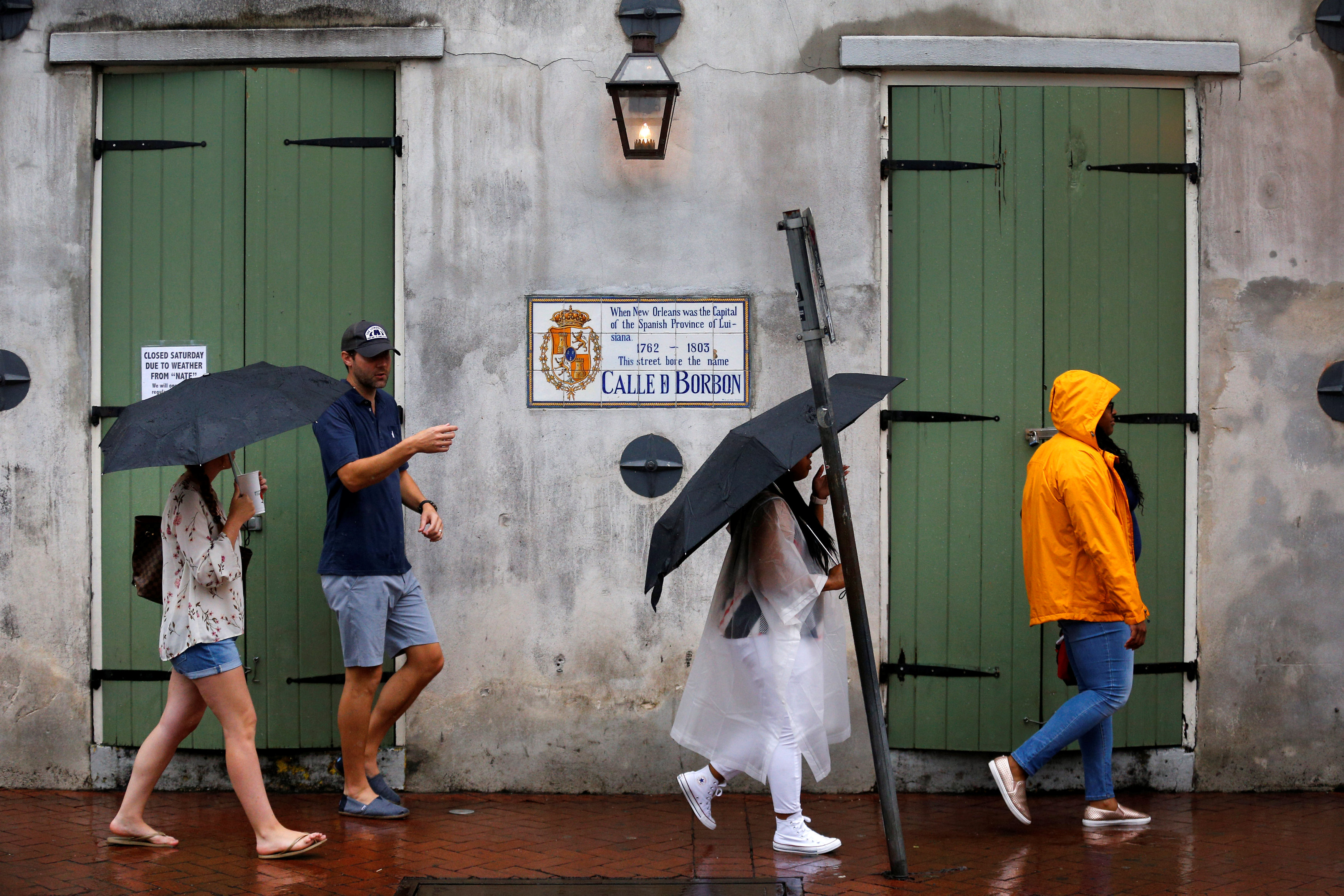مواطنون يستخدمون الملابس البلاستيكية والشمسيات لحمايتهم من الأمطار