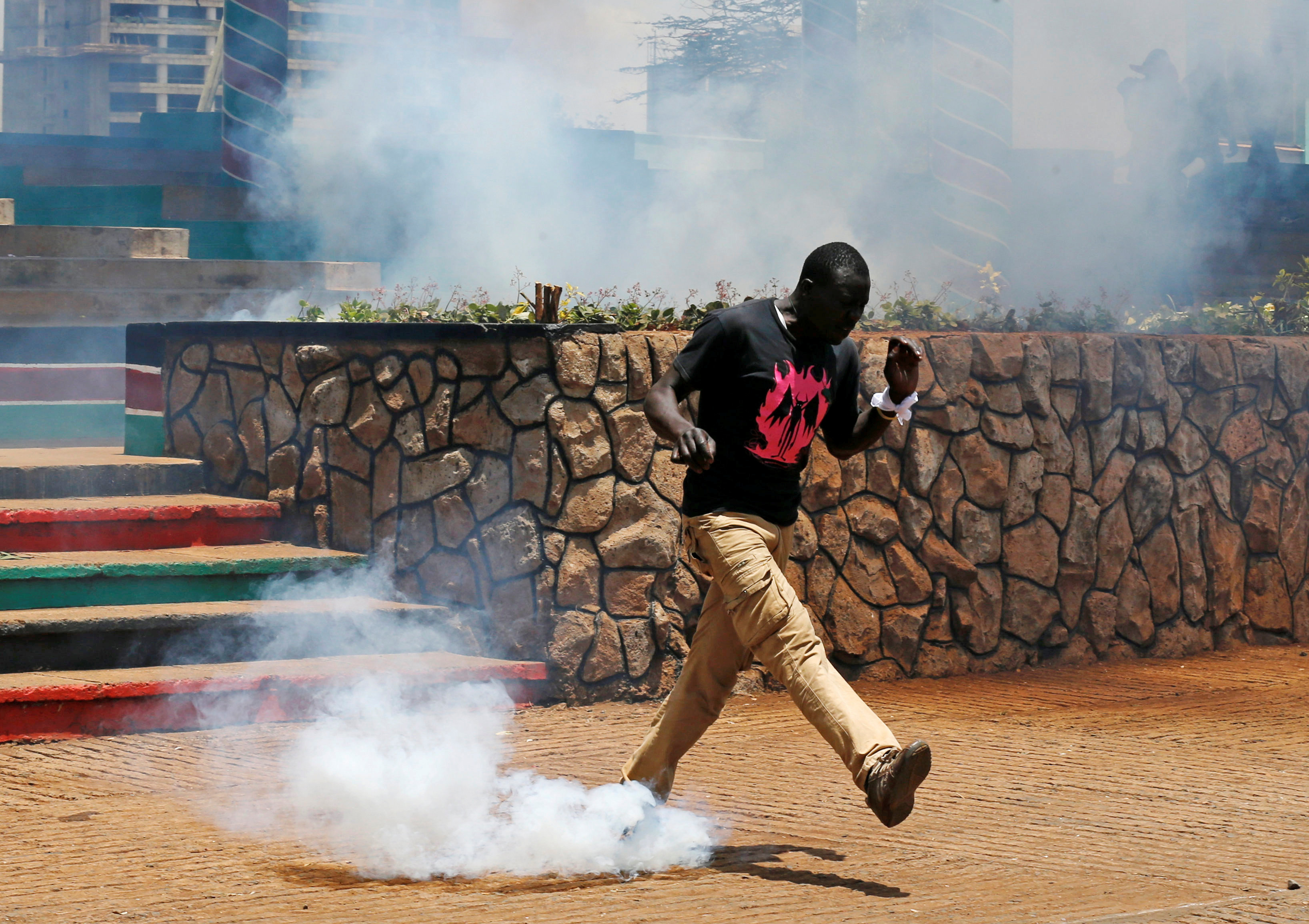 متظاهر يركل بقدمه قنبلة مسيلة للدموع