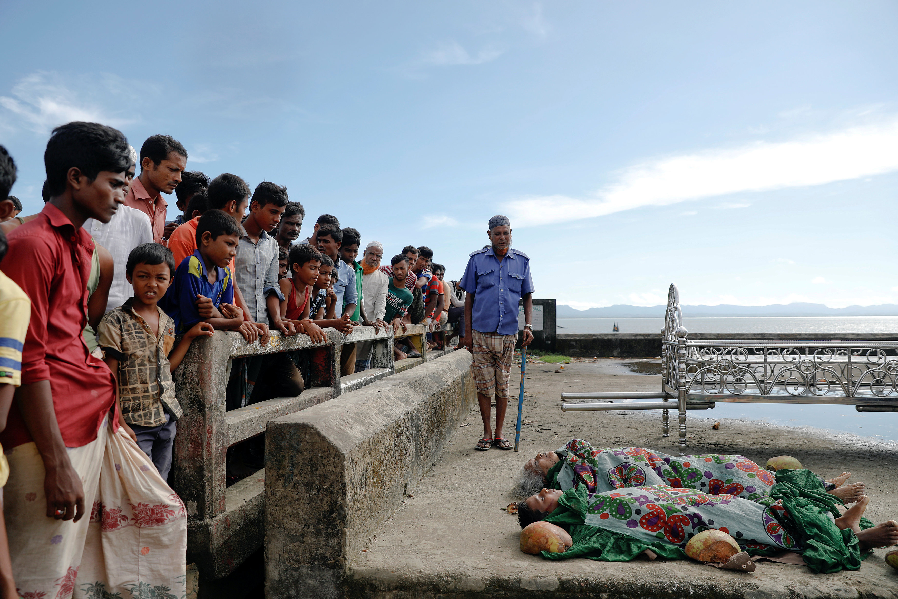 شباب وأطفال يقفون أمام جثامين ضحايا غرق مركب للروهينجا