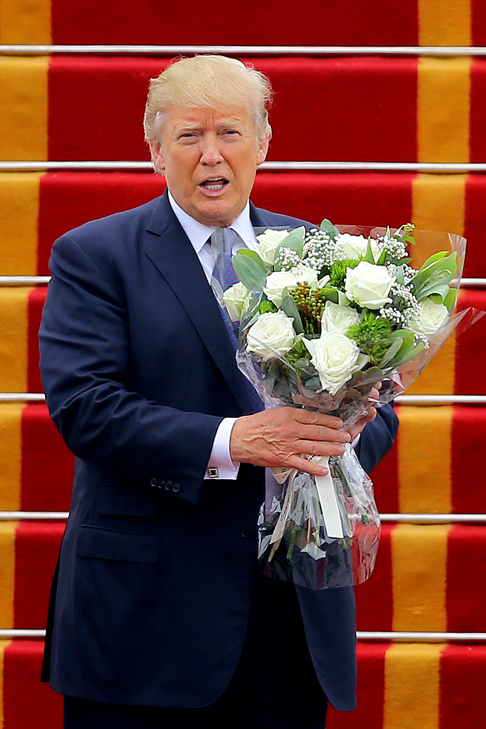 ترامب يحمل باقة ورد أثناء مغادرته فيتنام