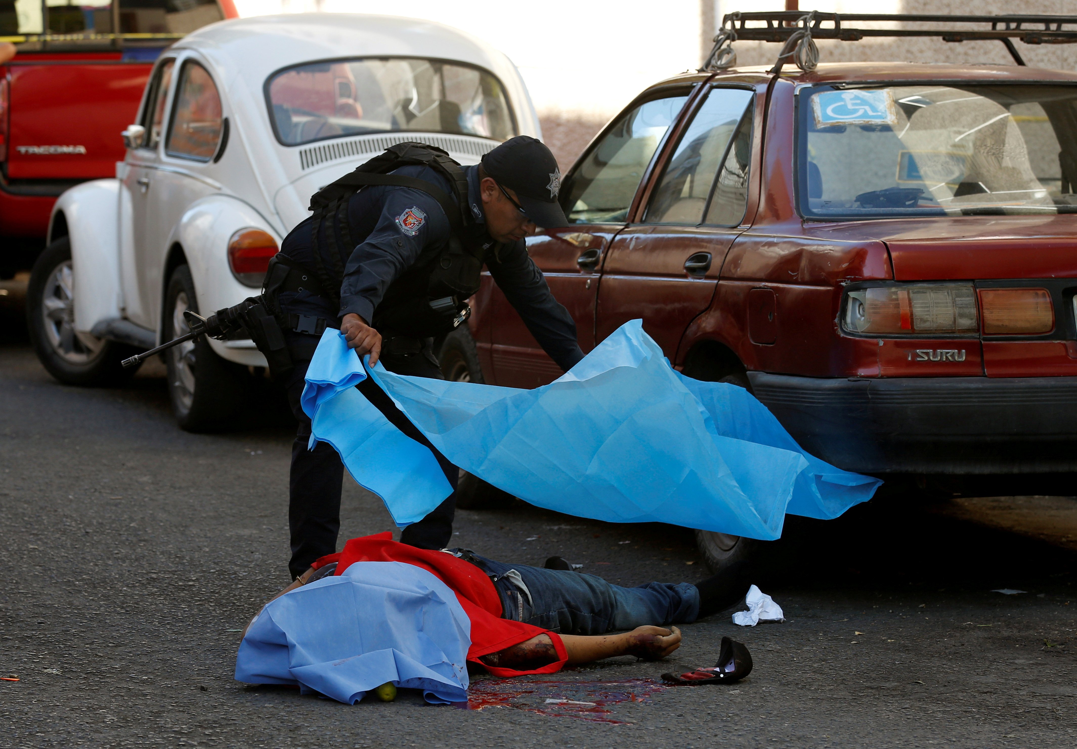 شرطى يغطى جثة القتيل