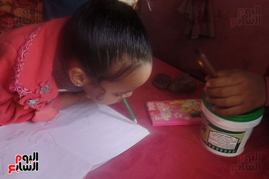 الطفلة تحاول الرسم بفمها