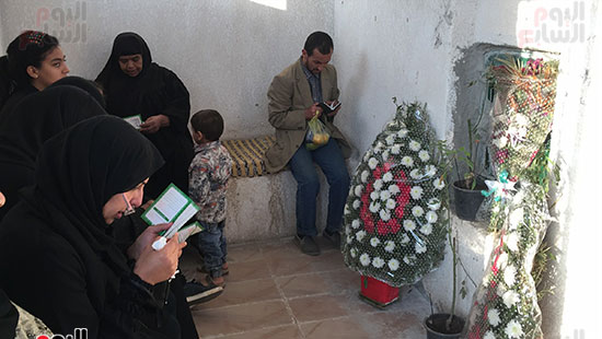 أسرة الشهيد تجلس بجوار قبره وتقرأ له القرآن
