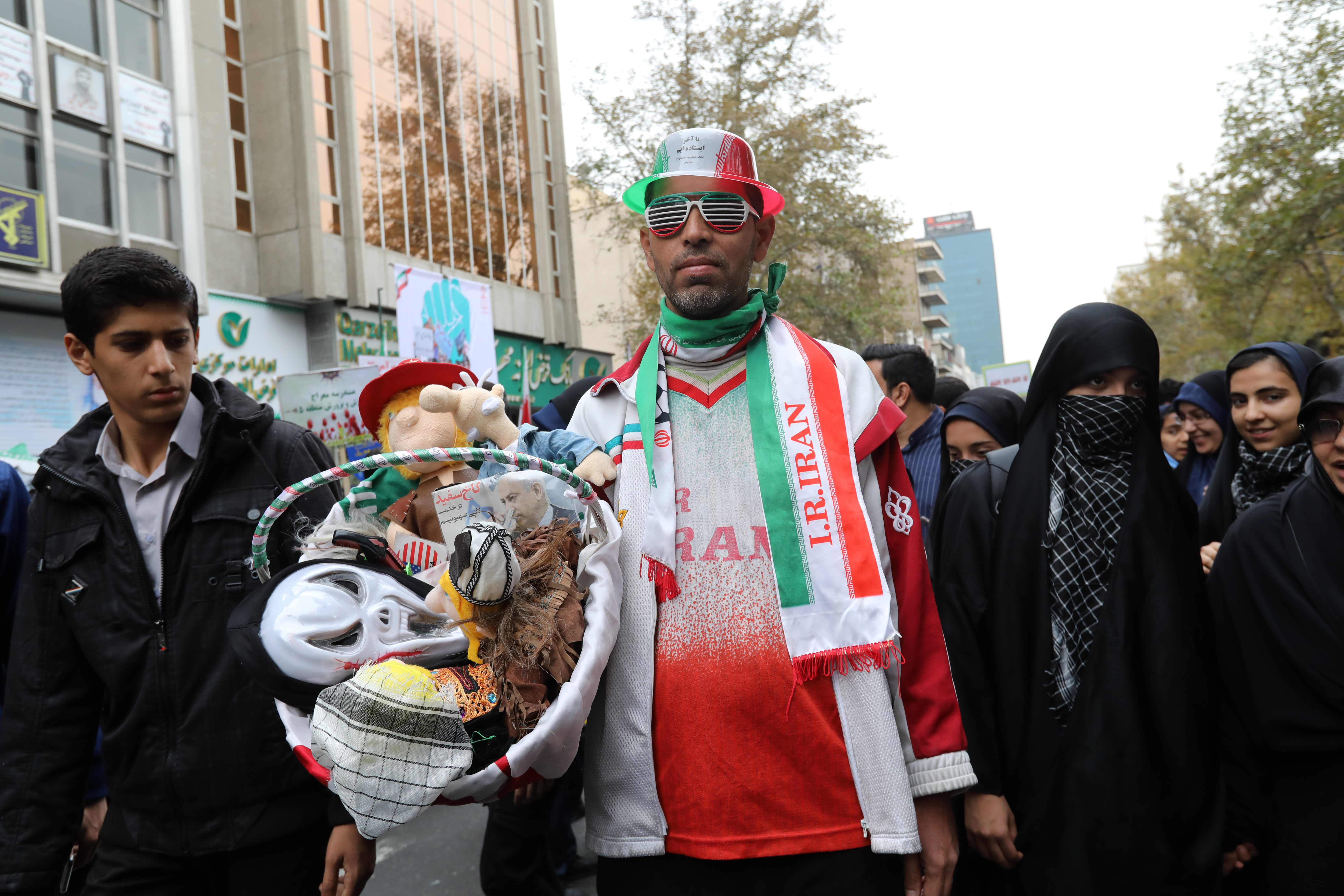 مواطن إيرانى يحمل أشكال استعراضية لترامب ونتنياهو