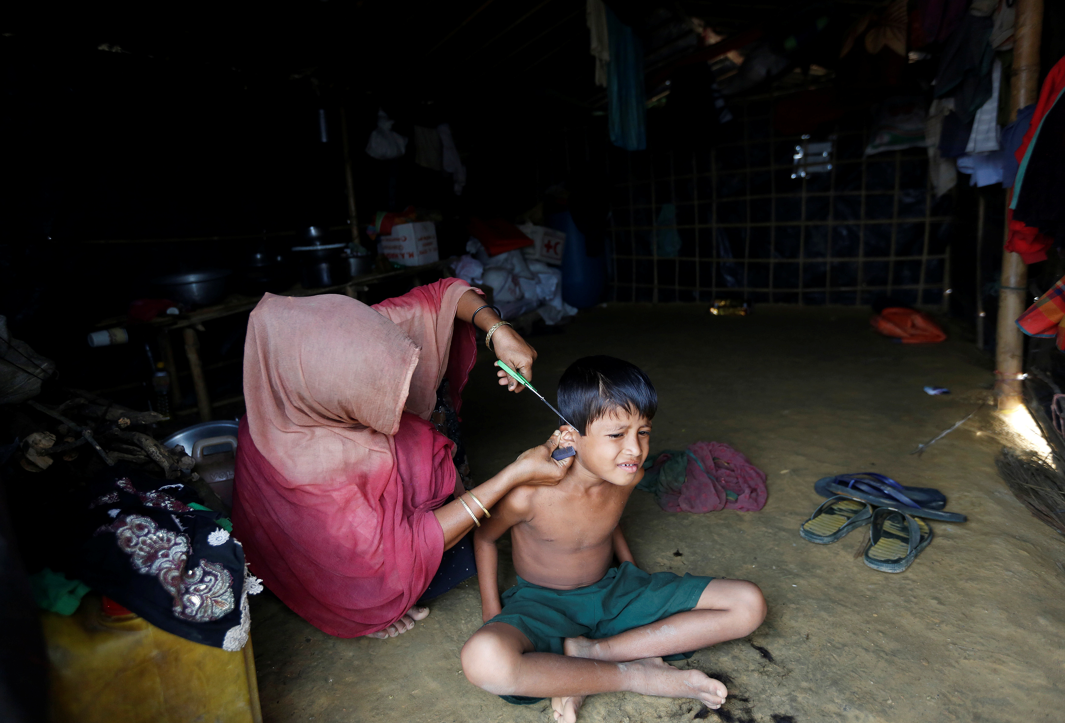 سيدة من الروهينجا تقص شعر ابنها داخل مخيمات بنجلادش