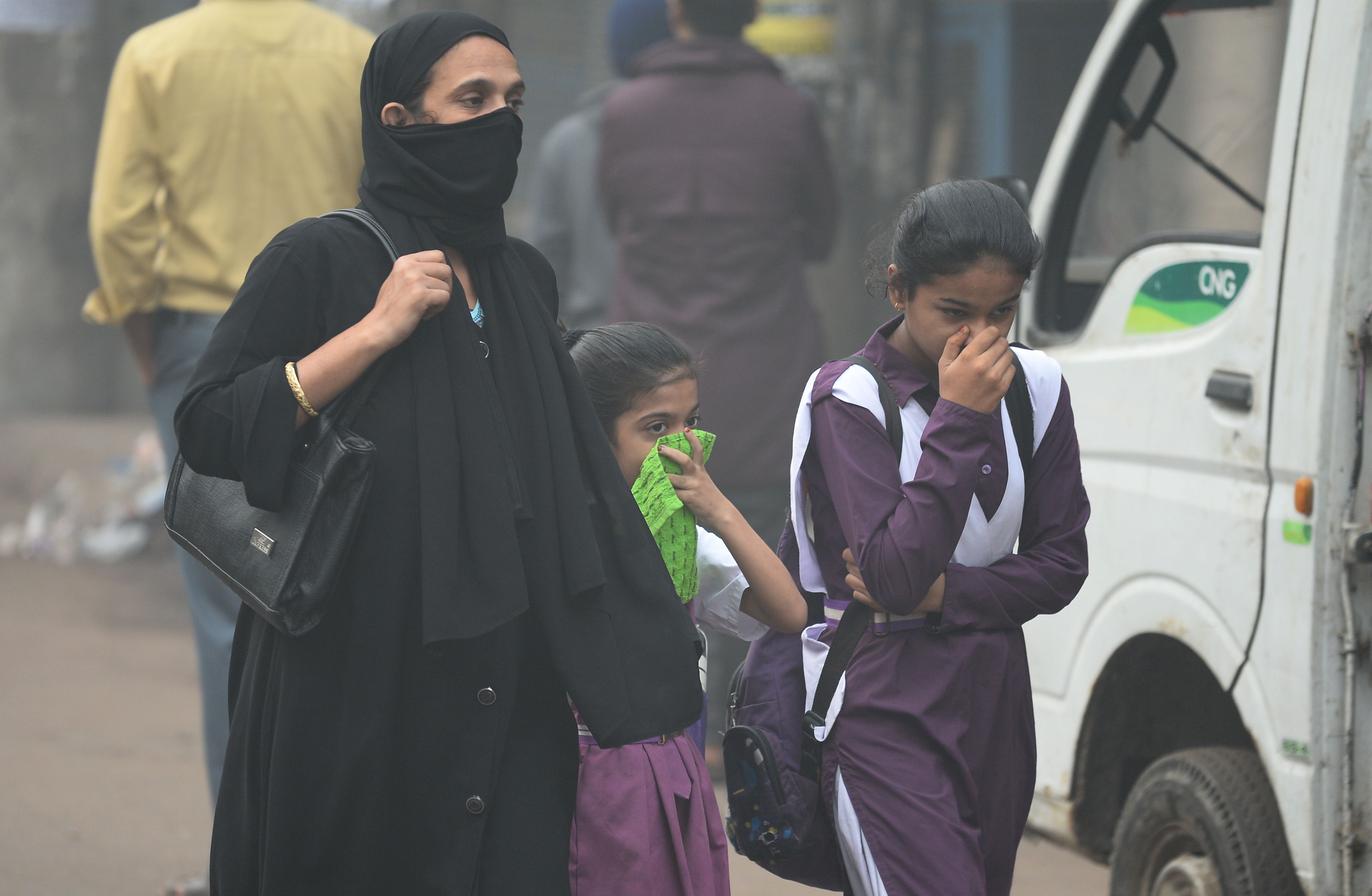 مواطنة هندية تسير بصحبة أطفالها وسط التلوث الدخانى