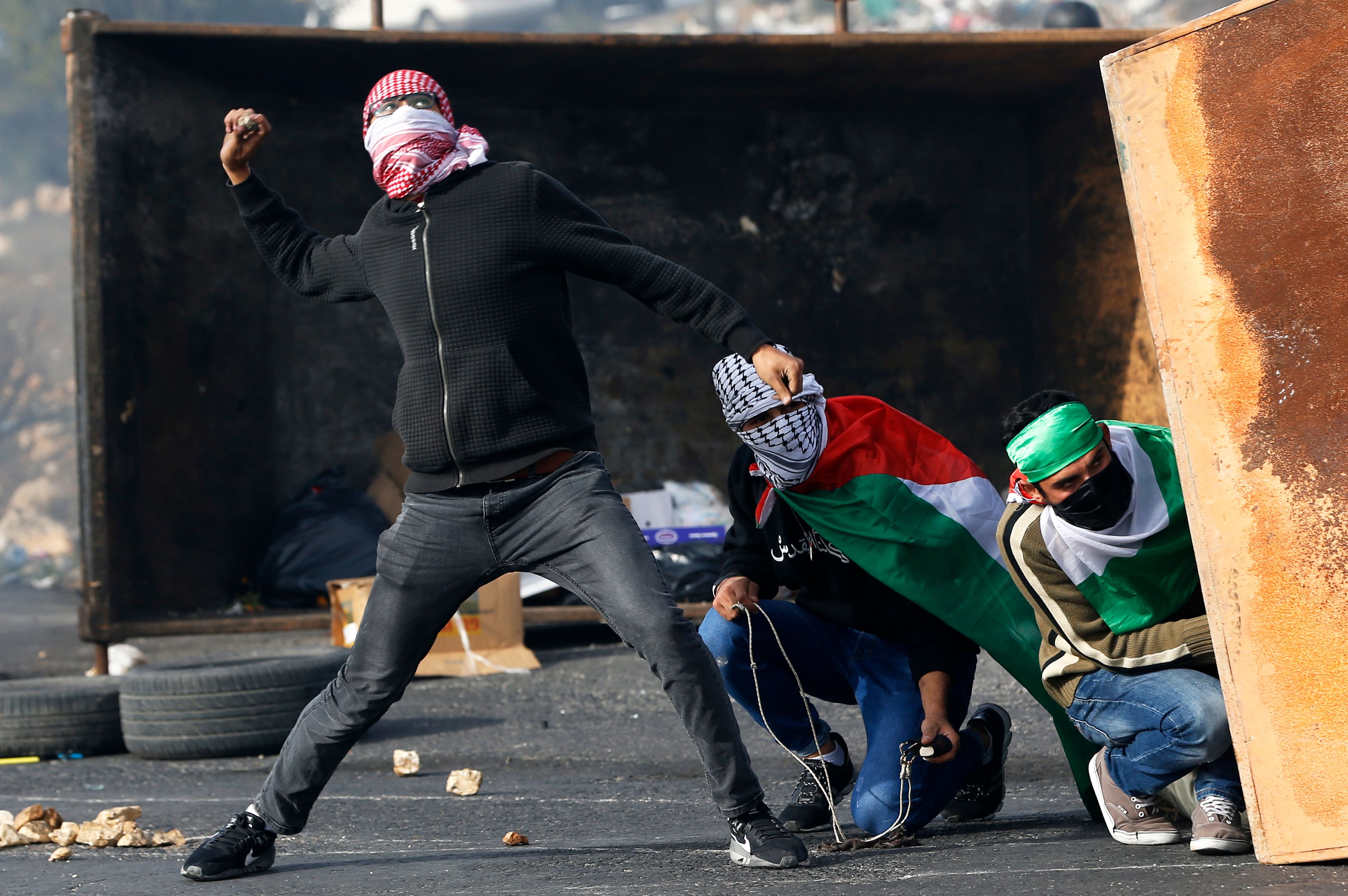 شاب فلسطينى يلقى الحجارة تجاه قوات  الاحتلال