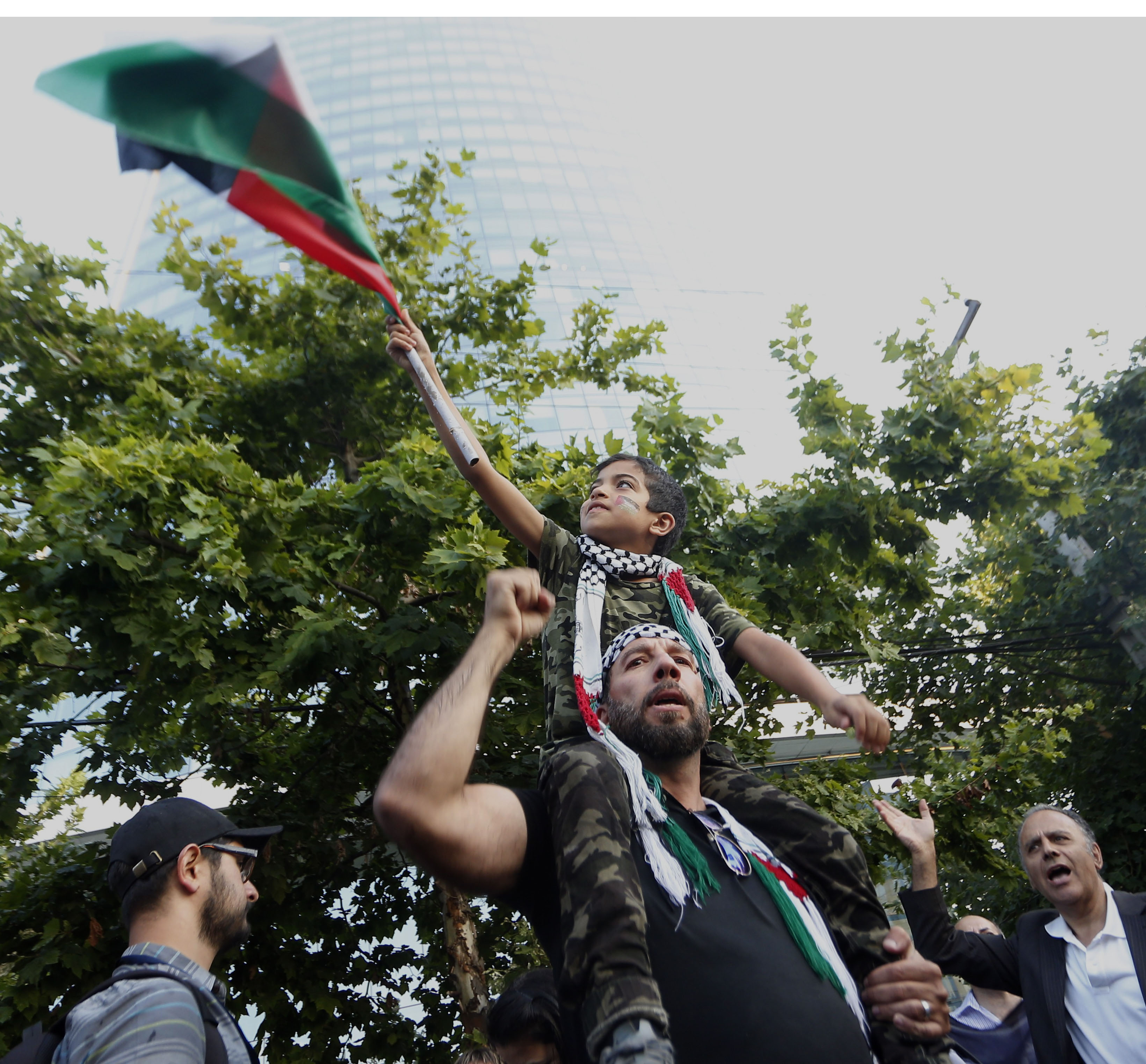 متظاهر يحمل ابنه رافعا علم فلسطين متظاهر يحمل ابنه رافعا علم فلسطين