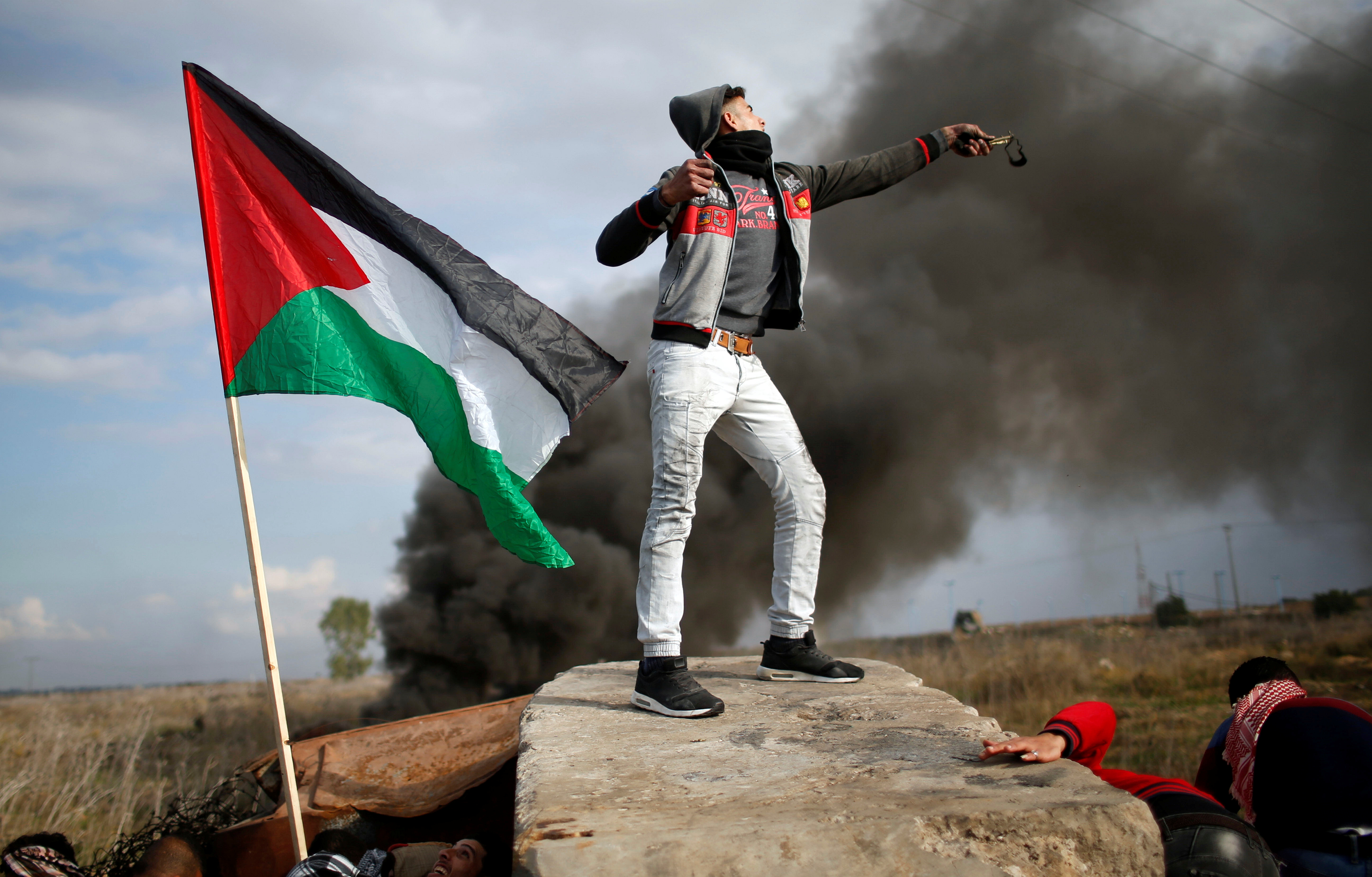شاب فلسطينى يتظاهر وبجواره علم بلاده