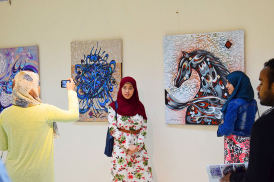  فتيات الاقصر يلتقطن صوراً مع لوحات المعرض السعودى
