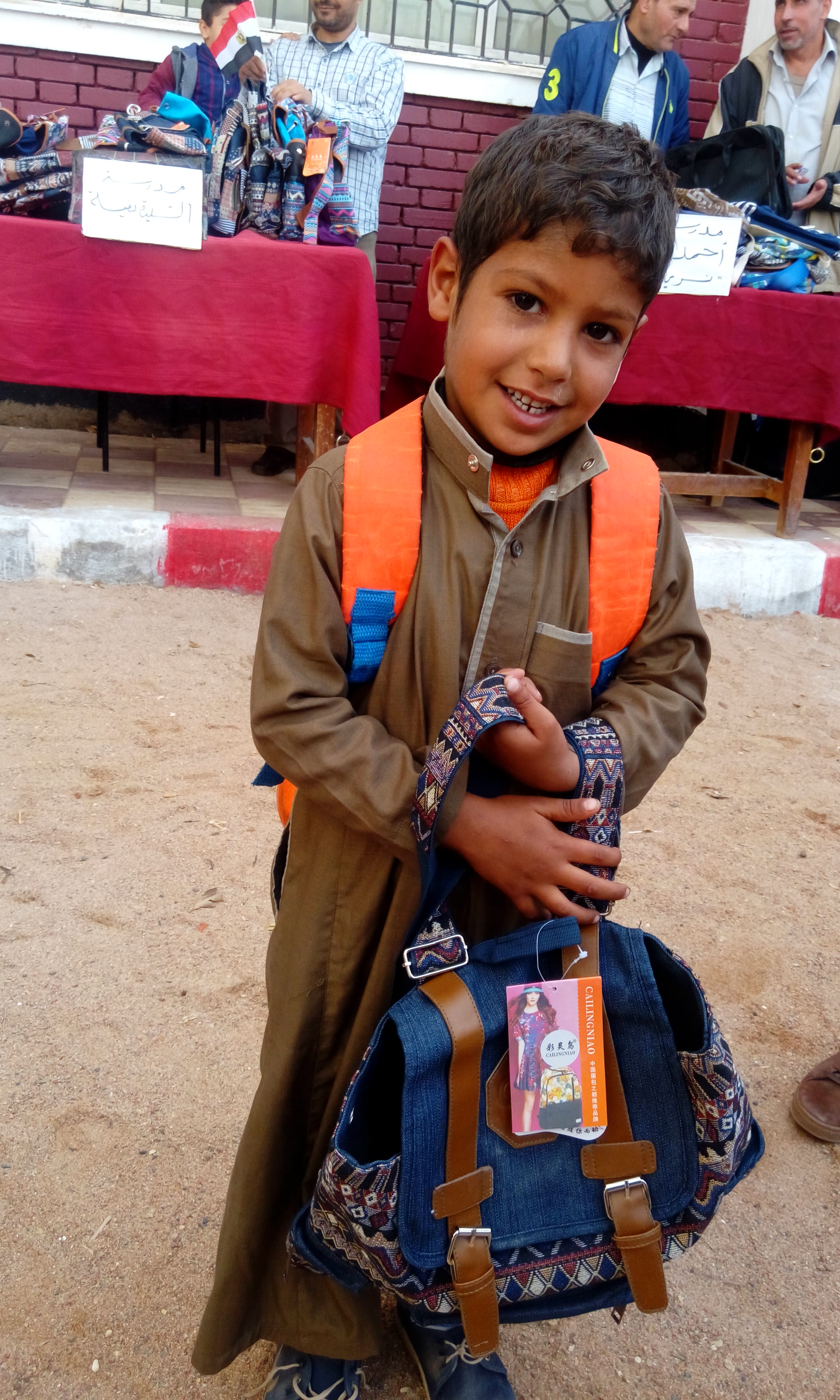 طفل يحمل شنطة الجمعية الاصدقاء