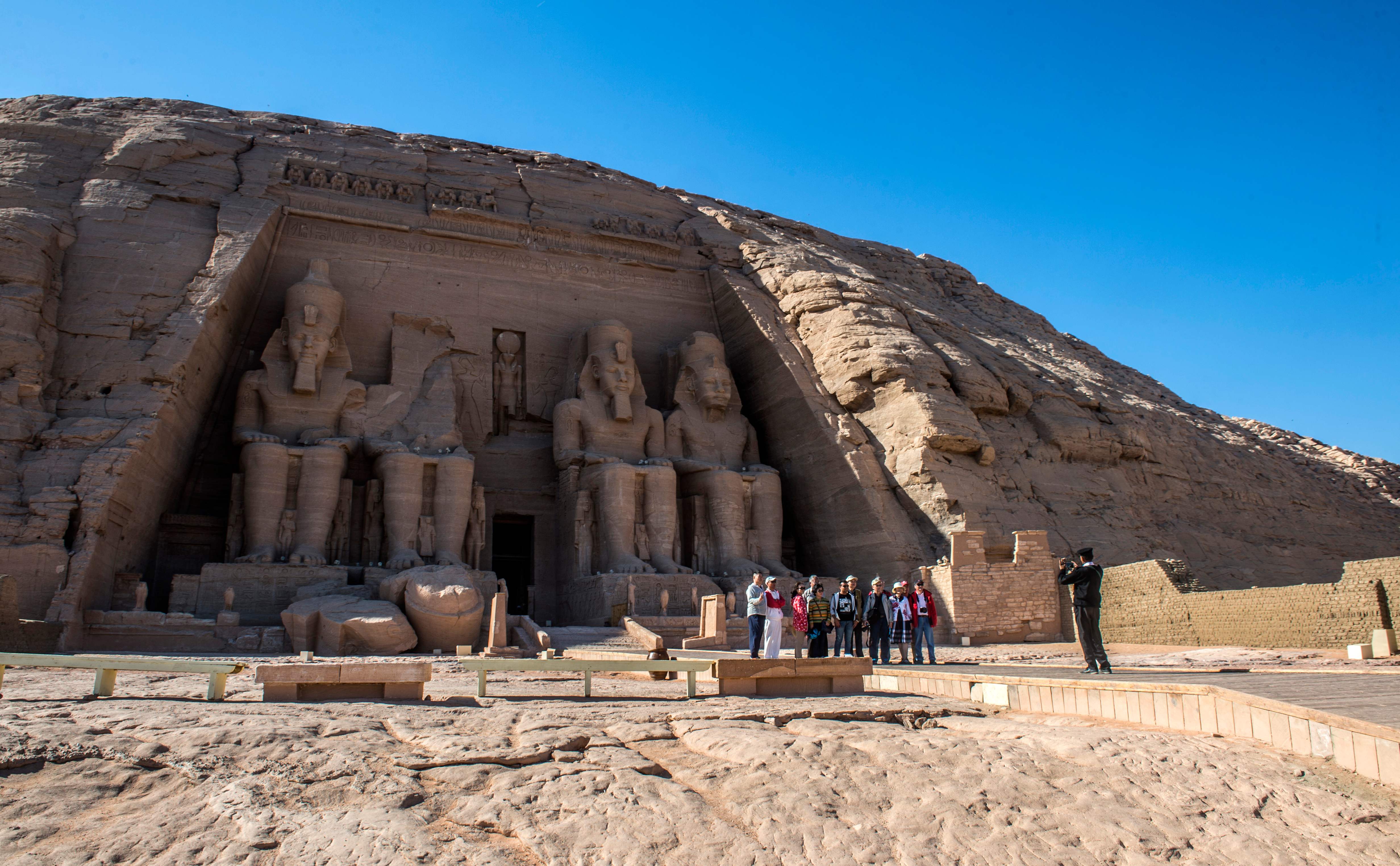 شرطى مصرى يلتقط صورة تذكارية لعدد من السياح أمام معبد أبو سمبل