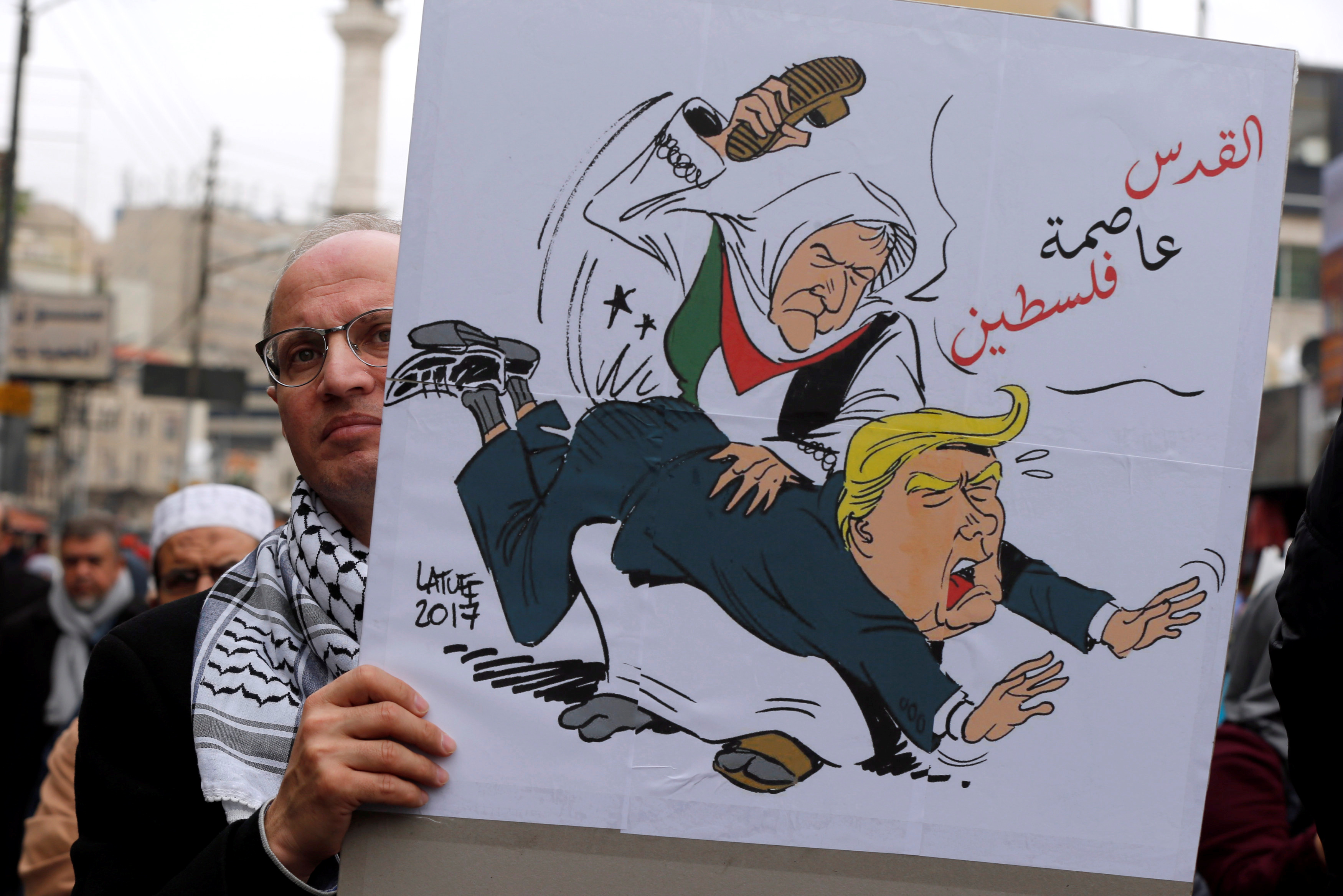 أحد المتظاهرين يرفع صورة لفلسطينى يضرب ترامب بالحذاء