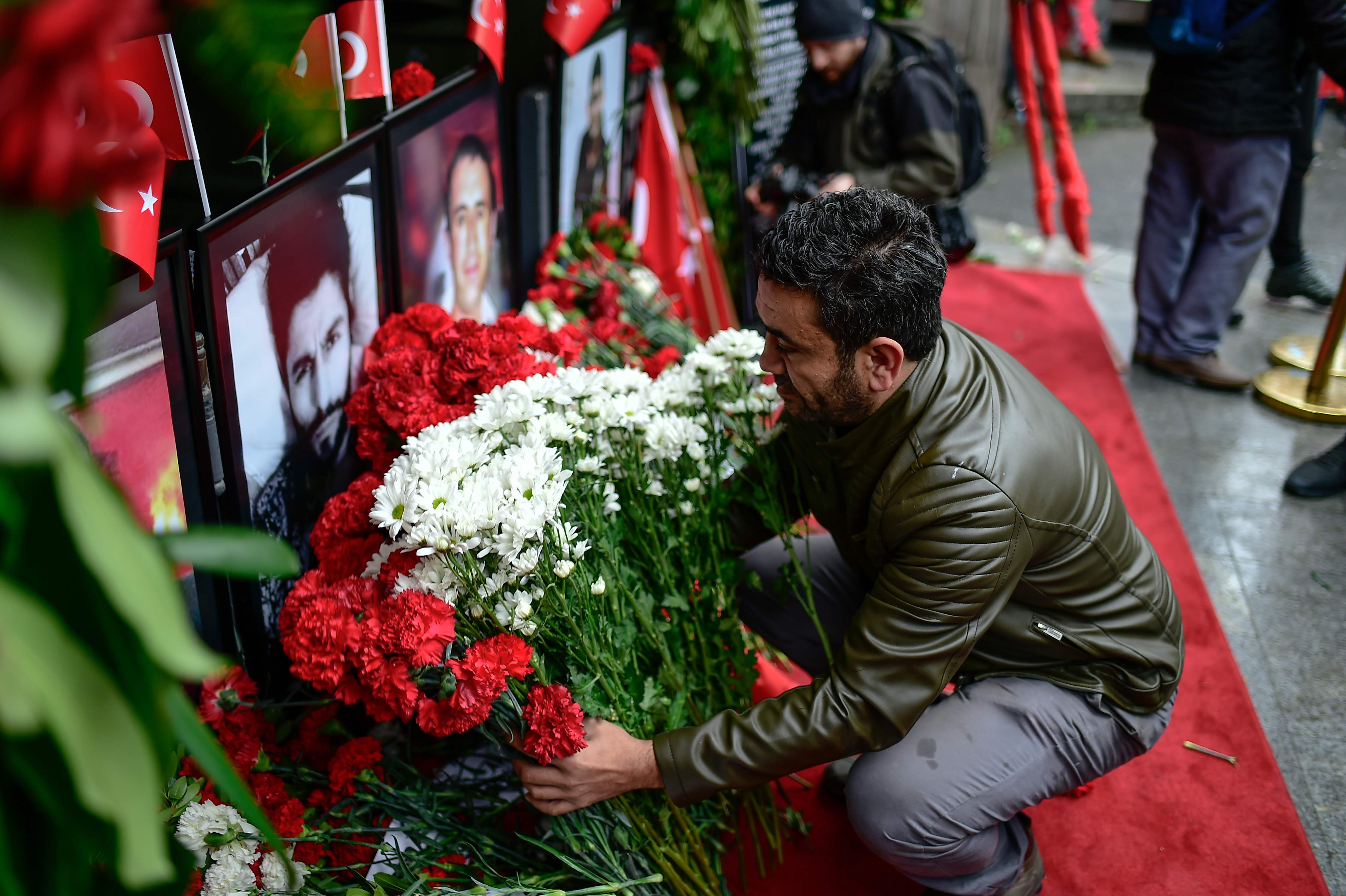 شاب يضع أكليل زهور أمام صور ضحايا هجوم اسطنبول
