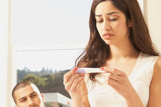 Hispanic couple with pregnancy test looking worried