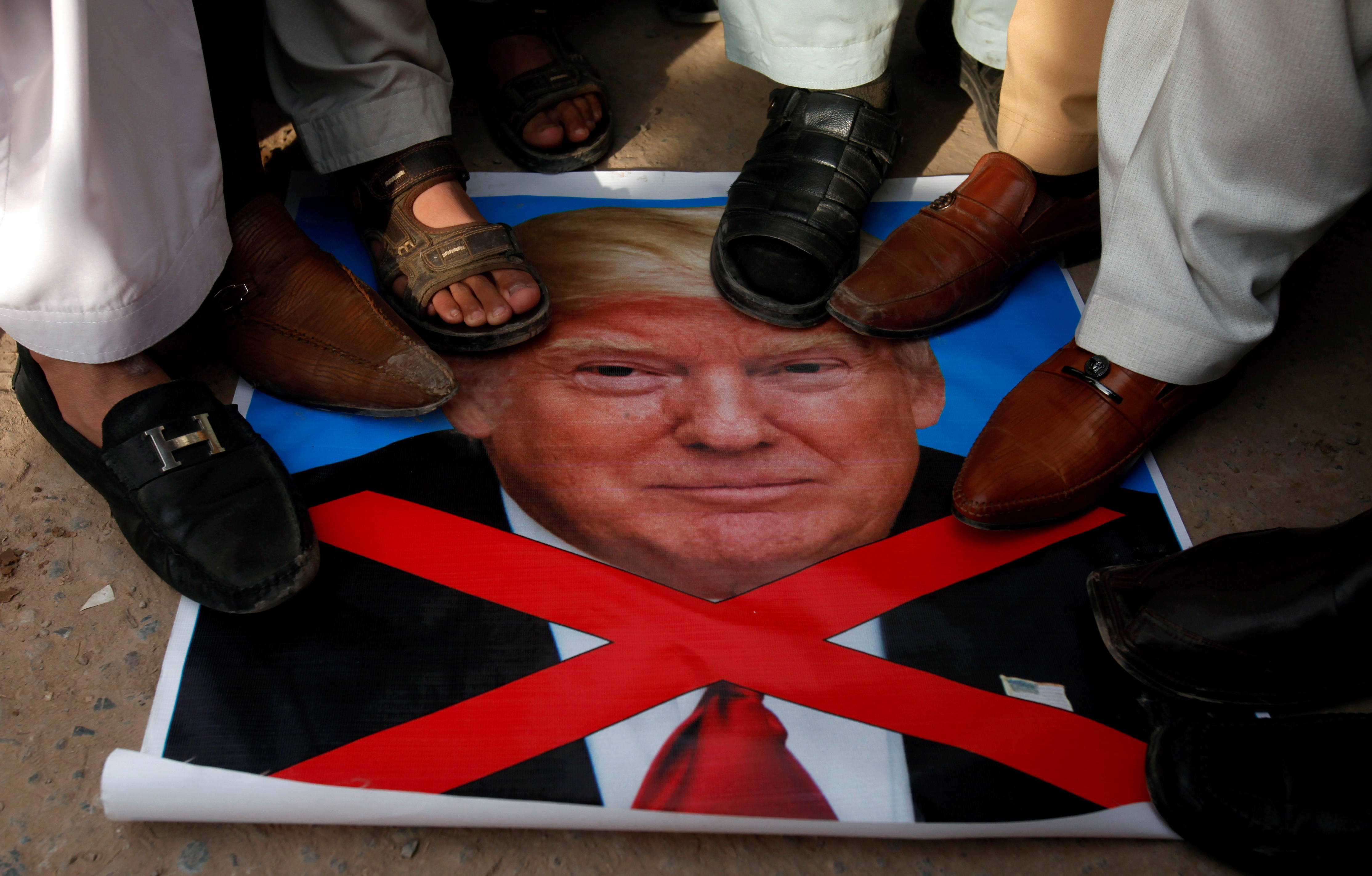 متظاهرون يضعون أحذيتهم على صورة لترامب