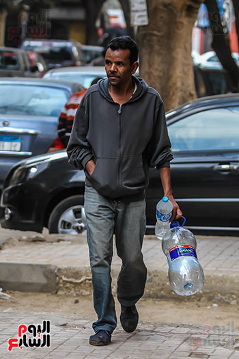 رجل يحمل زجاجات المياه الفارغة