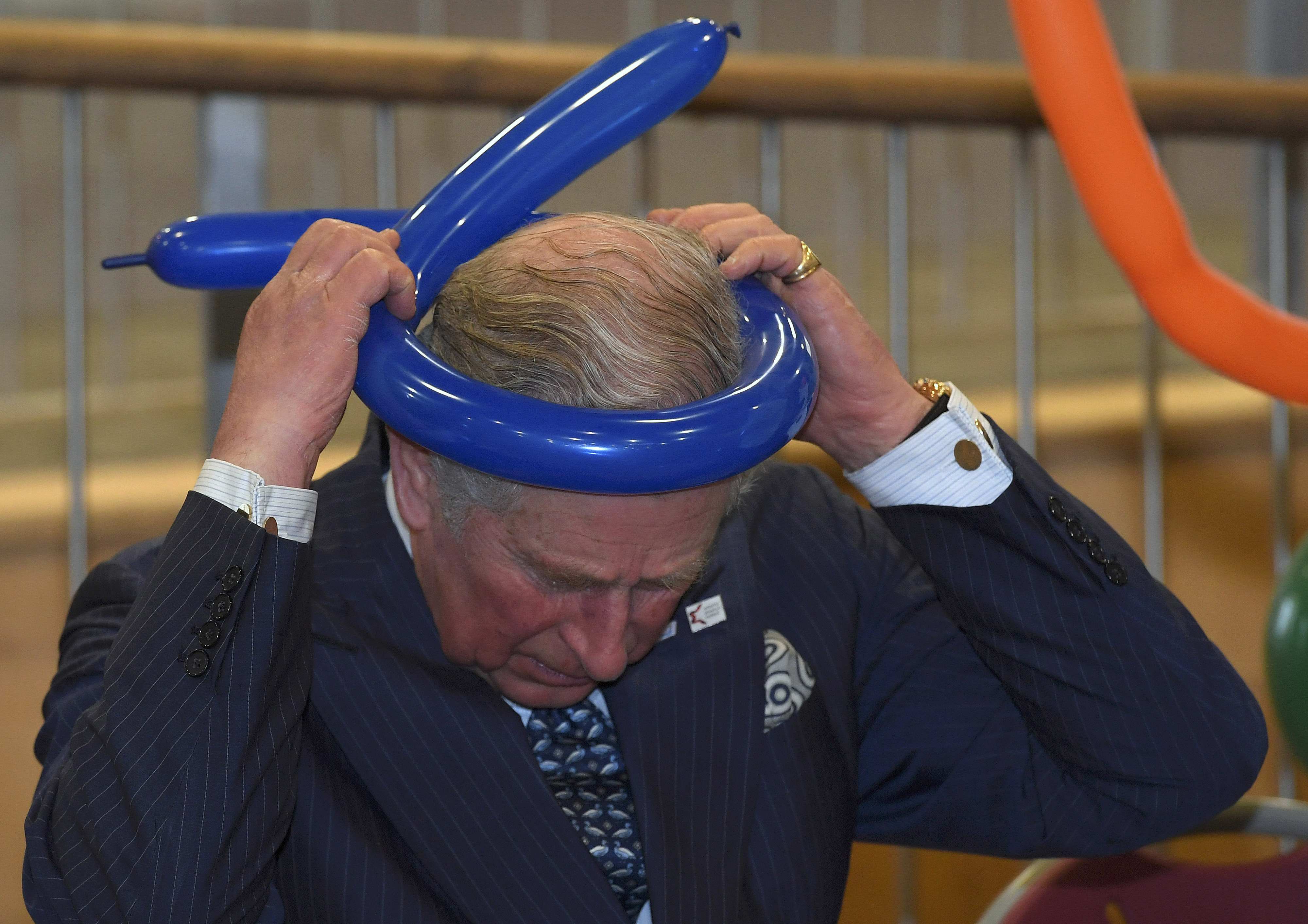 الأمير تشارلز يضع بالونه على رأسه خلال زياته لكلية يفنيه شمال لندن