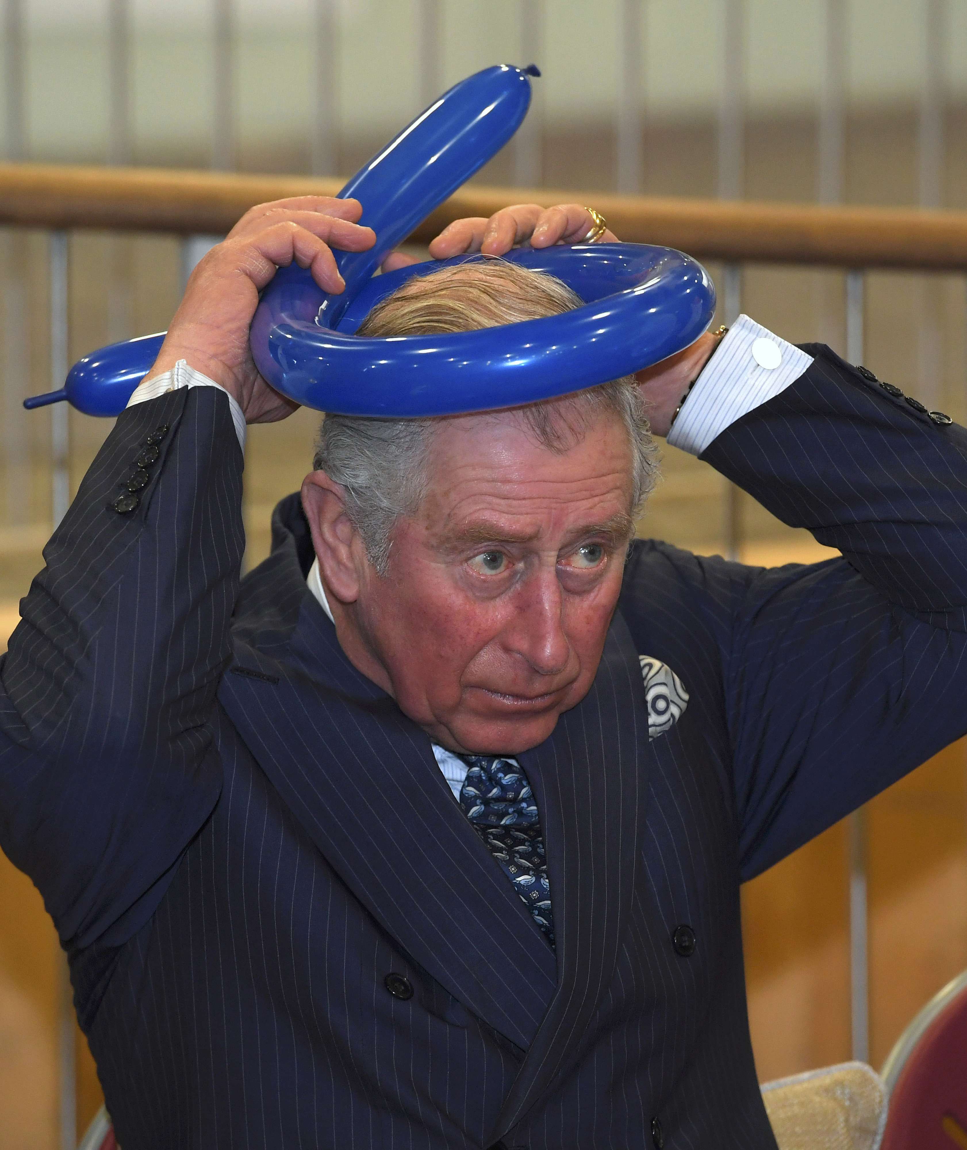 الأمير تشارلز يربط غطاء الرأس بالبالونة على رأسه فى زيارة لكلية يفنيه