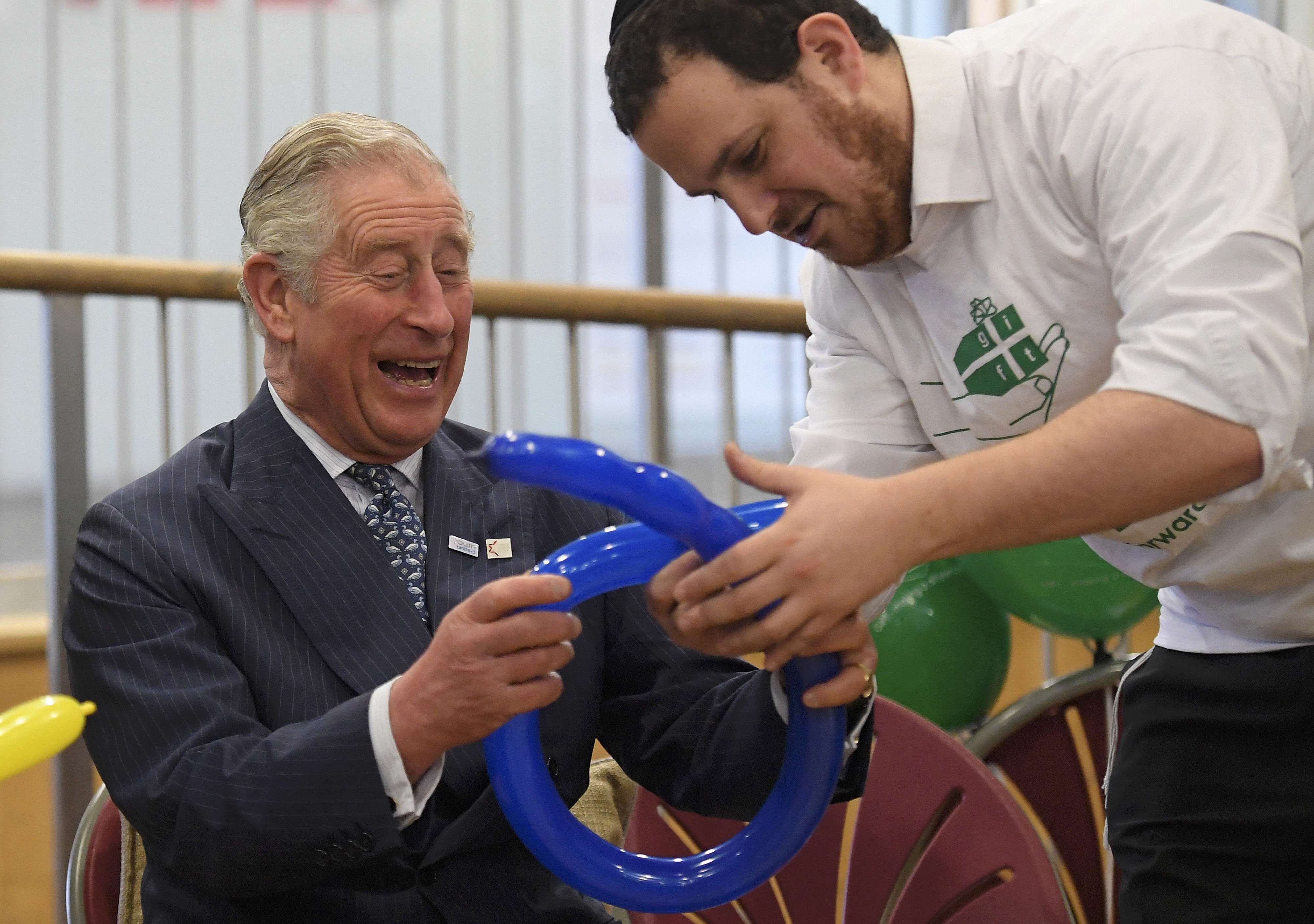 الأمير تشارلز يضحك خلال حضوره درس صناعة أغطية الرأس بالبالونات فى كلية يفنيه شمال لندن