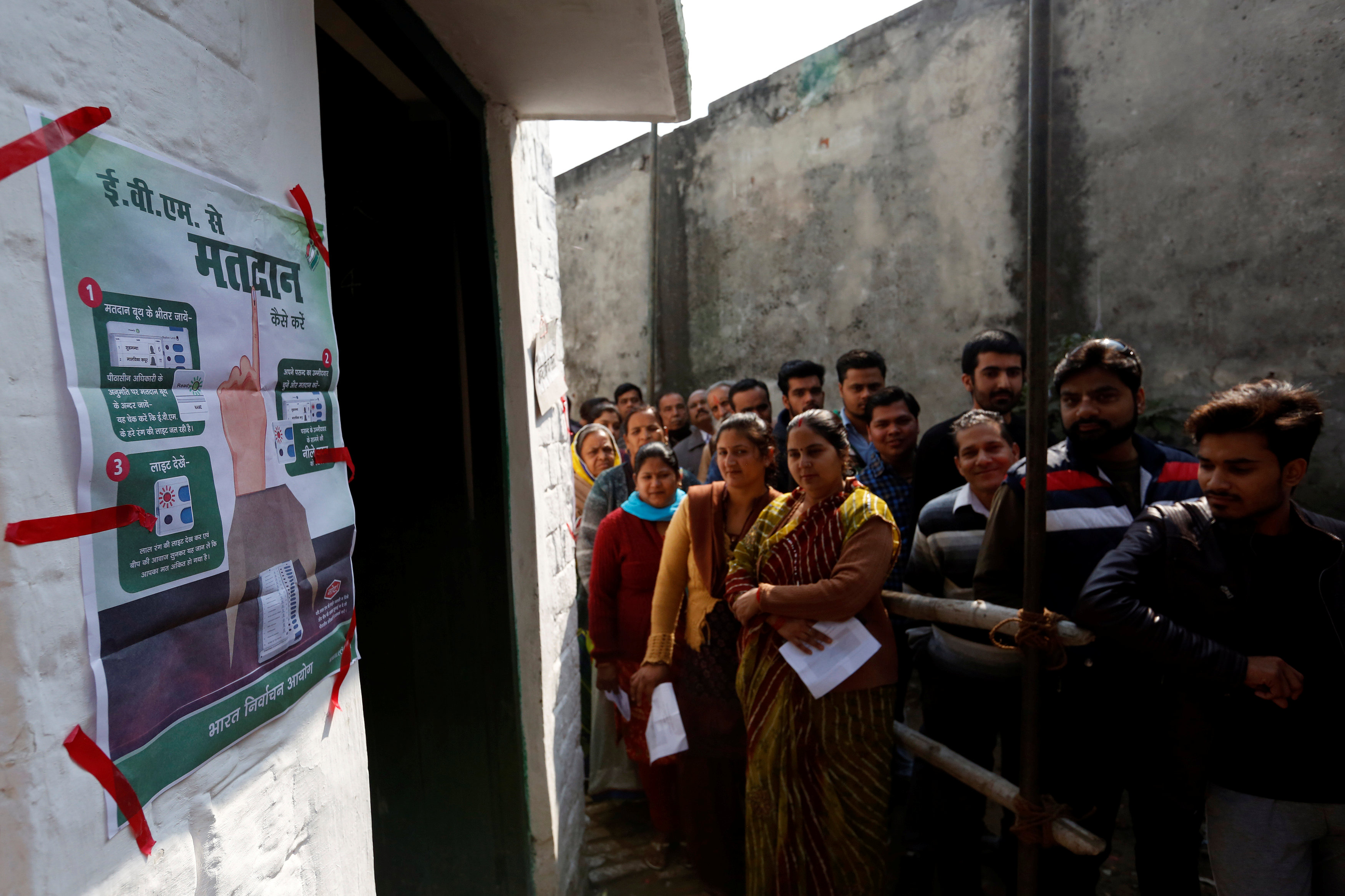 ناخبون يقفون أمام لوحة الإرشادات الخاصة بانتخابات حكومة محلية فى الهند