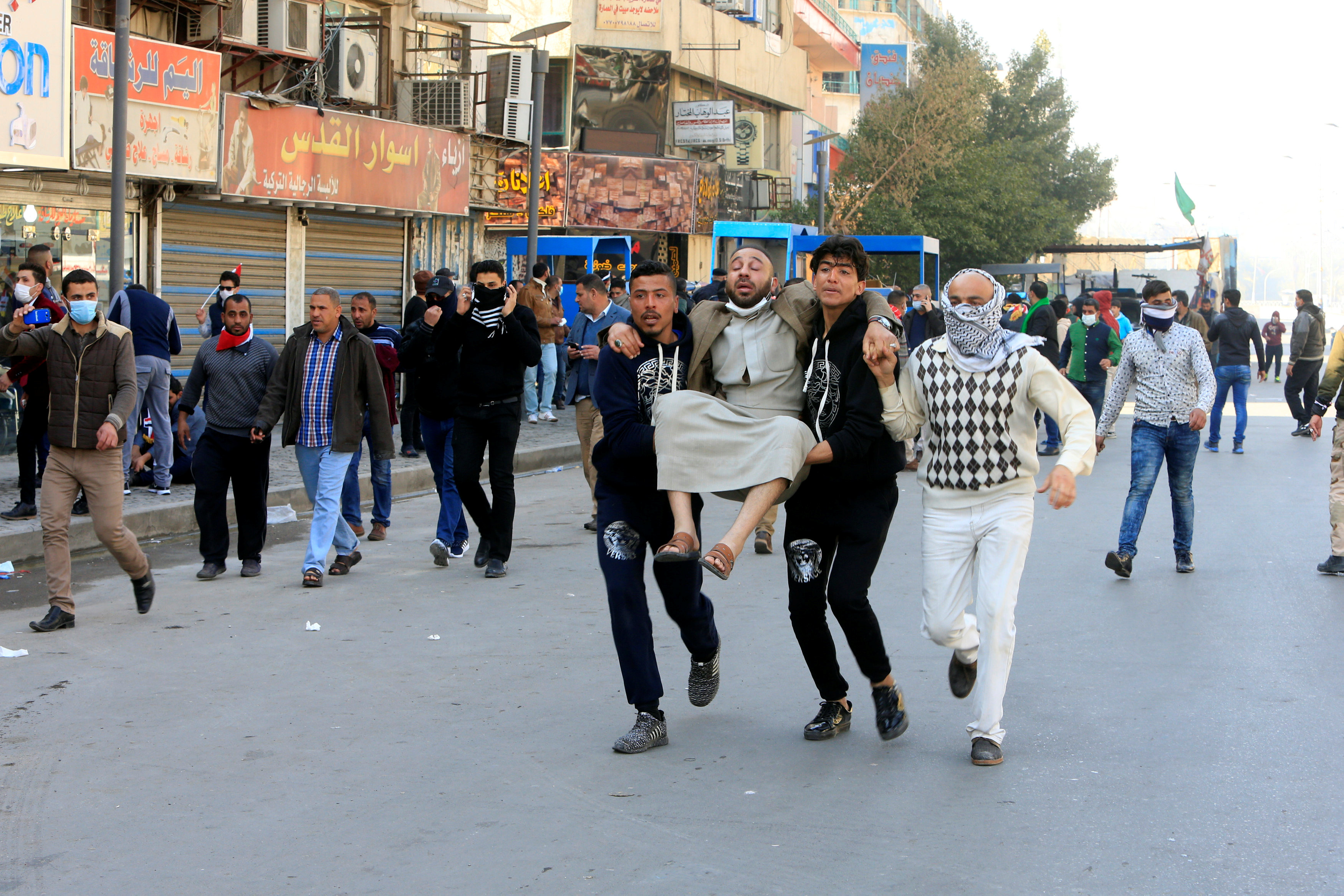 متظاهرون يحملون مصابًا فى اشتباكات مع الشرطة العراقية فى ساحة التحرير