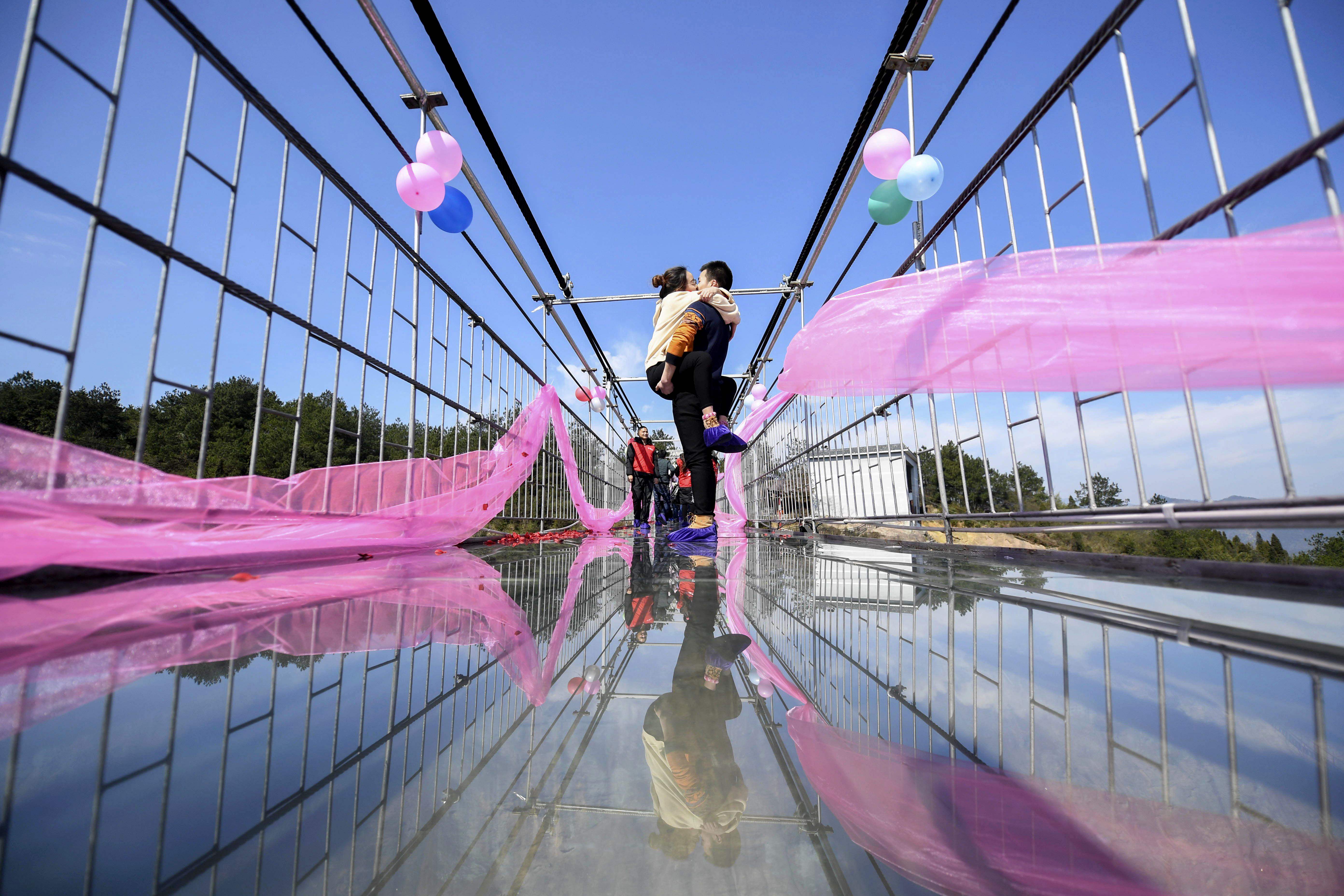 شاب يحمل حبيبته ويقبلها أعلى جسر زجاجى فى الصين بمناسبة عيد الحب
