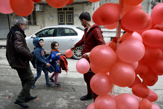 شاب يوزع البالونات الحمراء على الأطفال فى سوريا بمناسبة عيد الحب