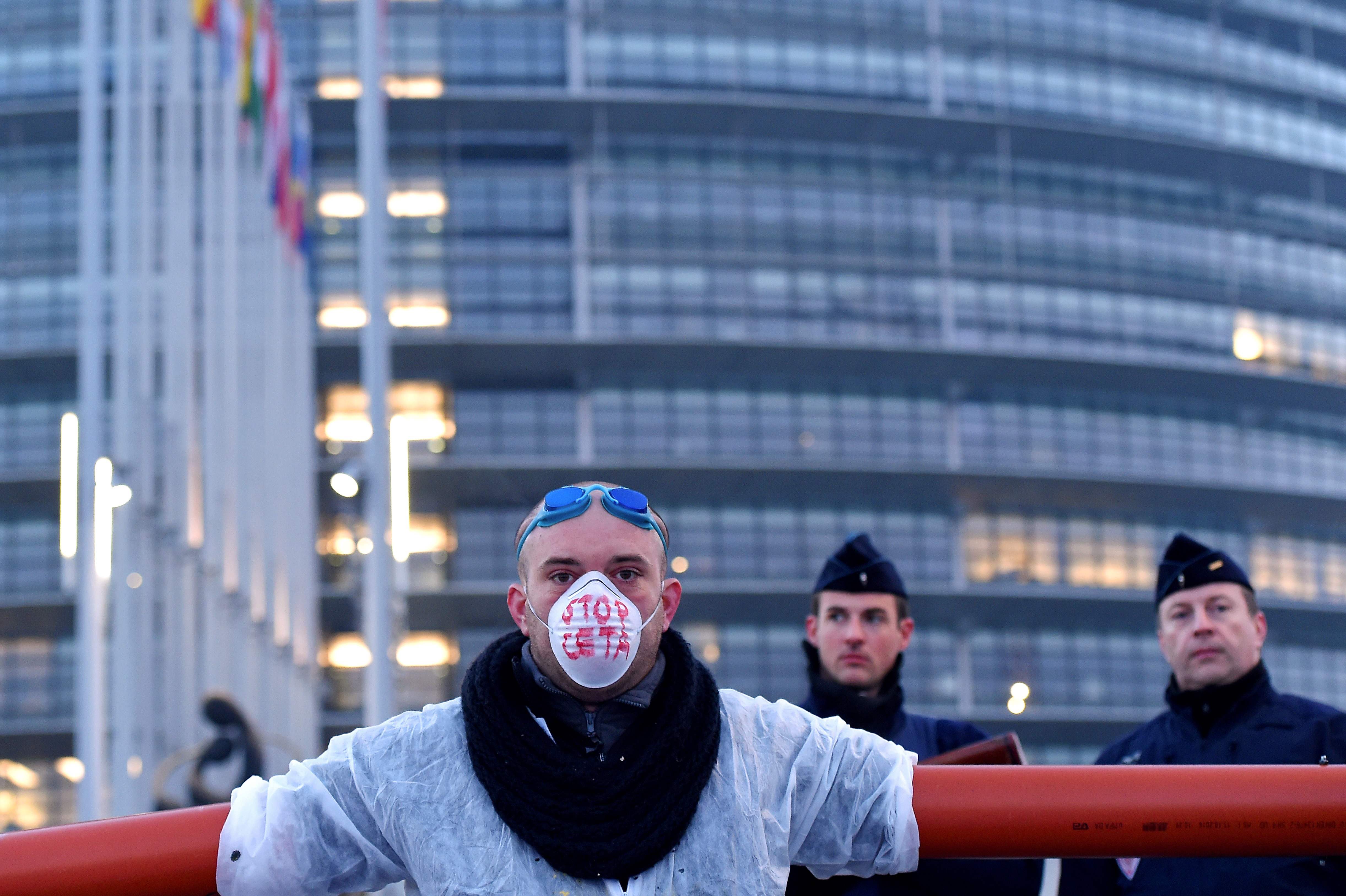 متظاهر يقف أمام الشرطة الفرنسية بمحيط البرلمان الأوروبى للاحتجاج على اتفاقية اقتصادية بين الاتحاد الأوروبى وكندا