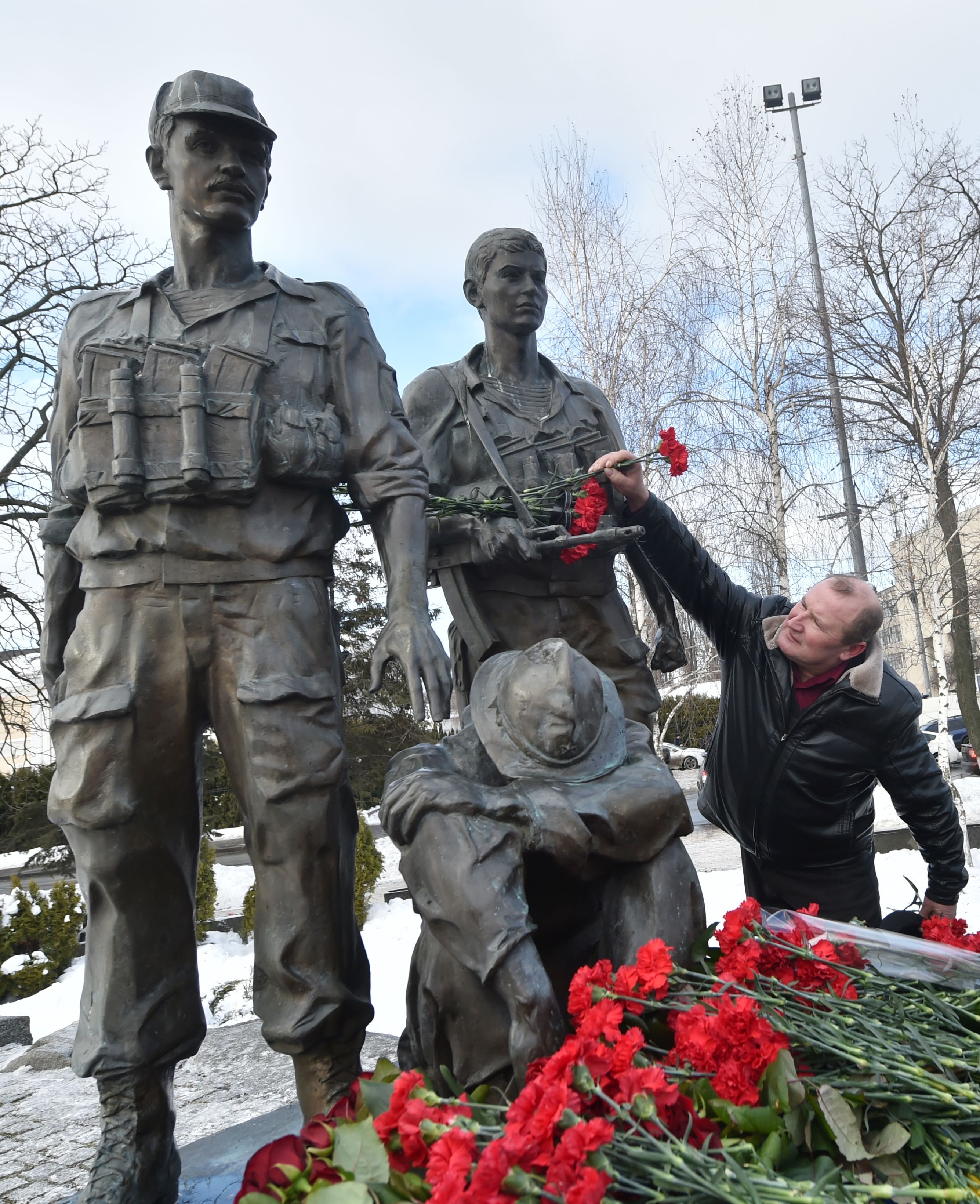 أحد المحاربين القدامى يضع ورد على تمثال بالنصب التذكارى لضحايا الحرب السوفيتية