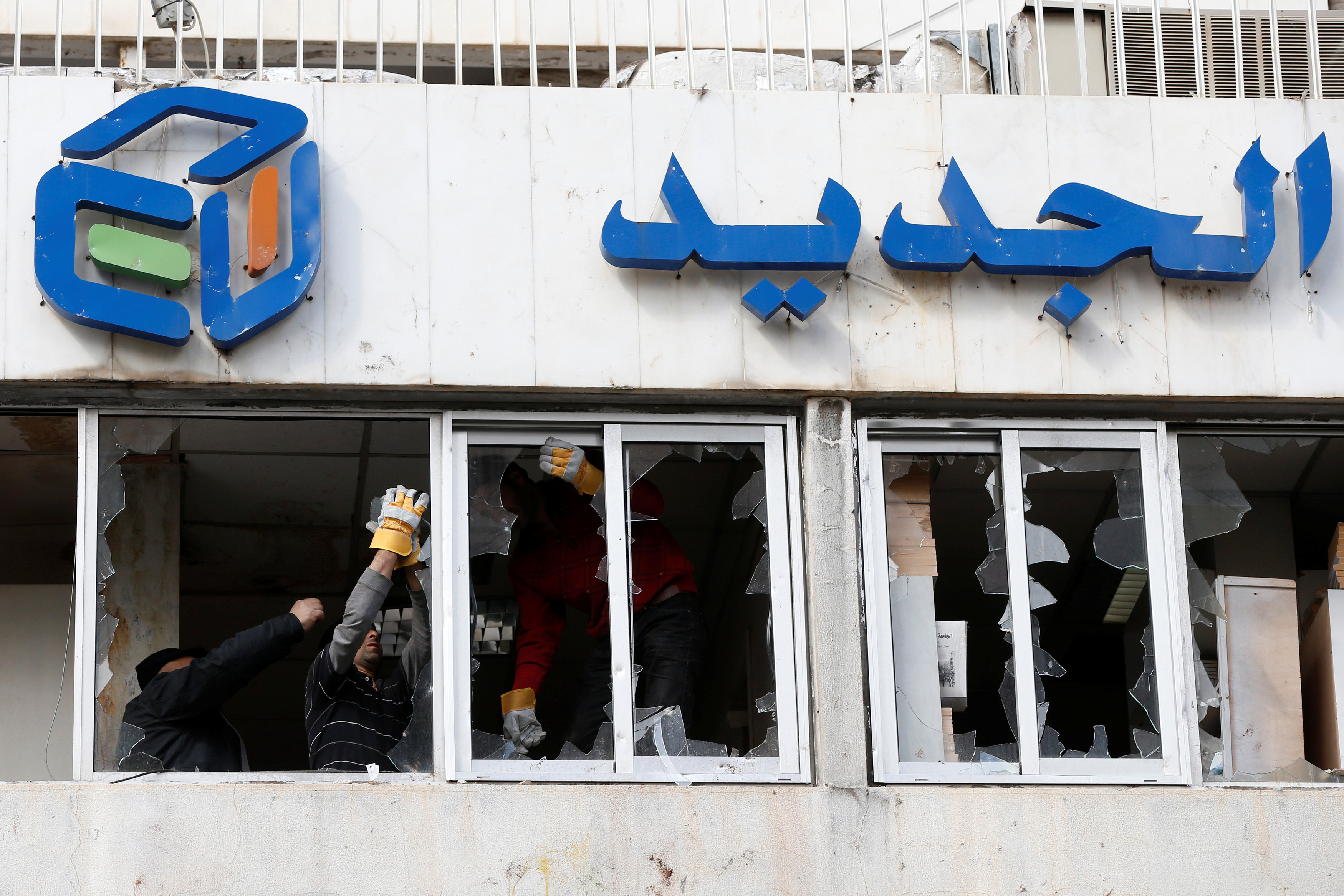 عمال يزيلون الزجاج المحطم على واجهة قناة الجديد اللبنانية