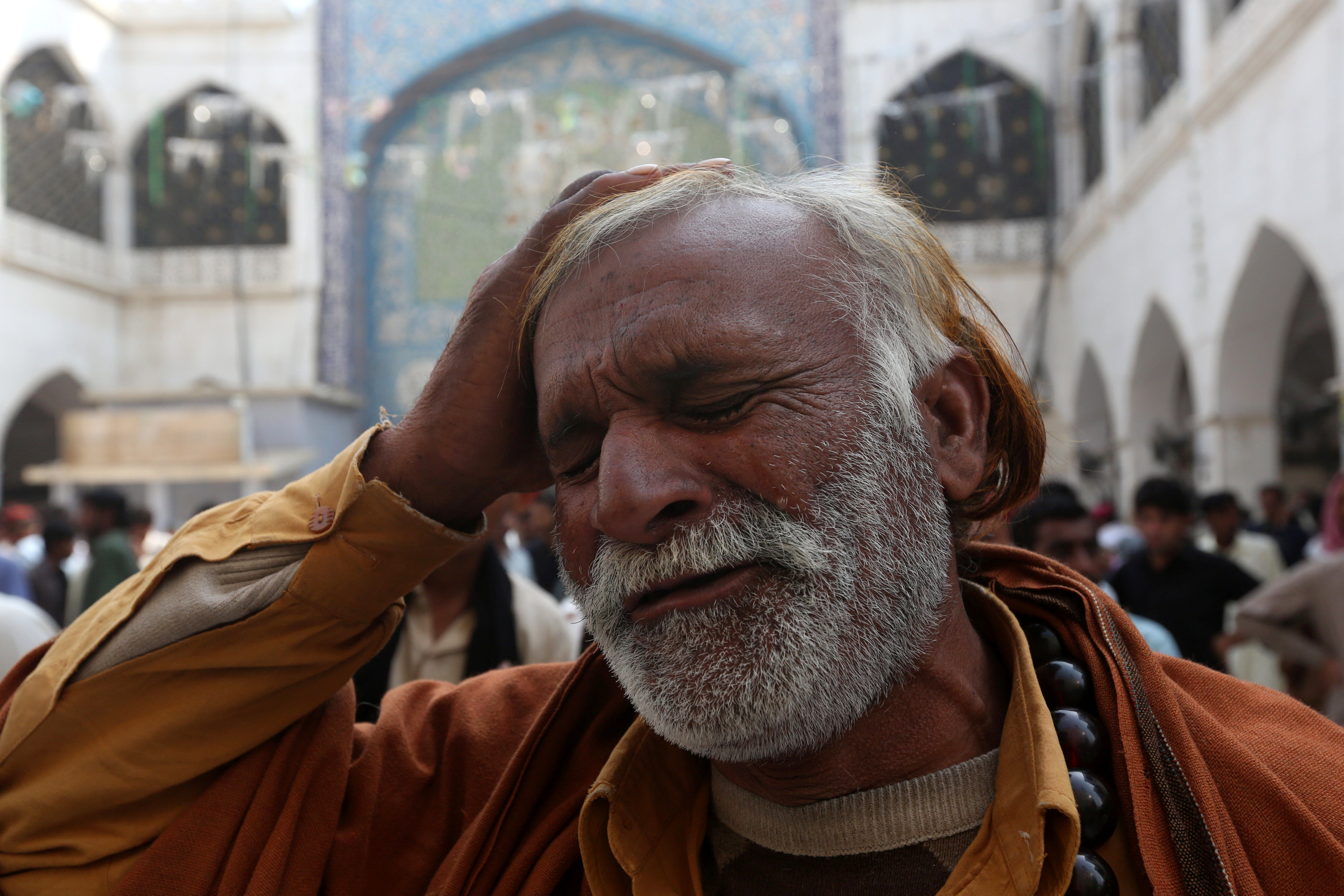 رجل يخبط على رأسه لفقدانه أحد أقاربه فى تفجير ضريح صوفى بباكستان