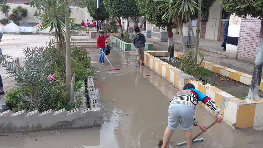 طلاب المدرسة ينزحون مياه الأمطار
