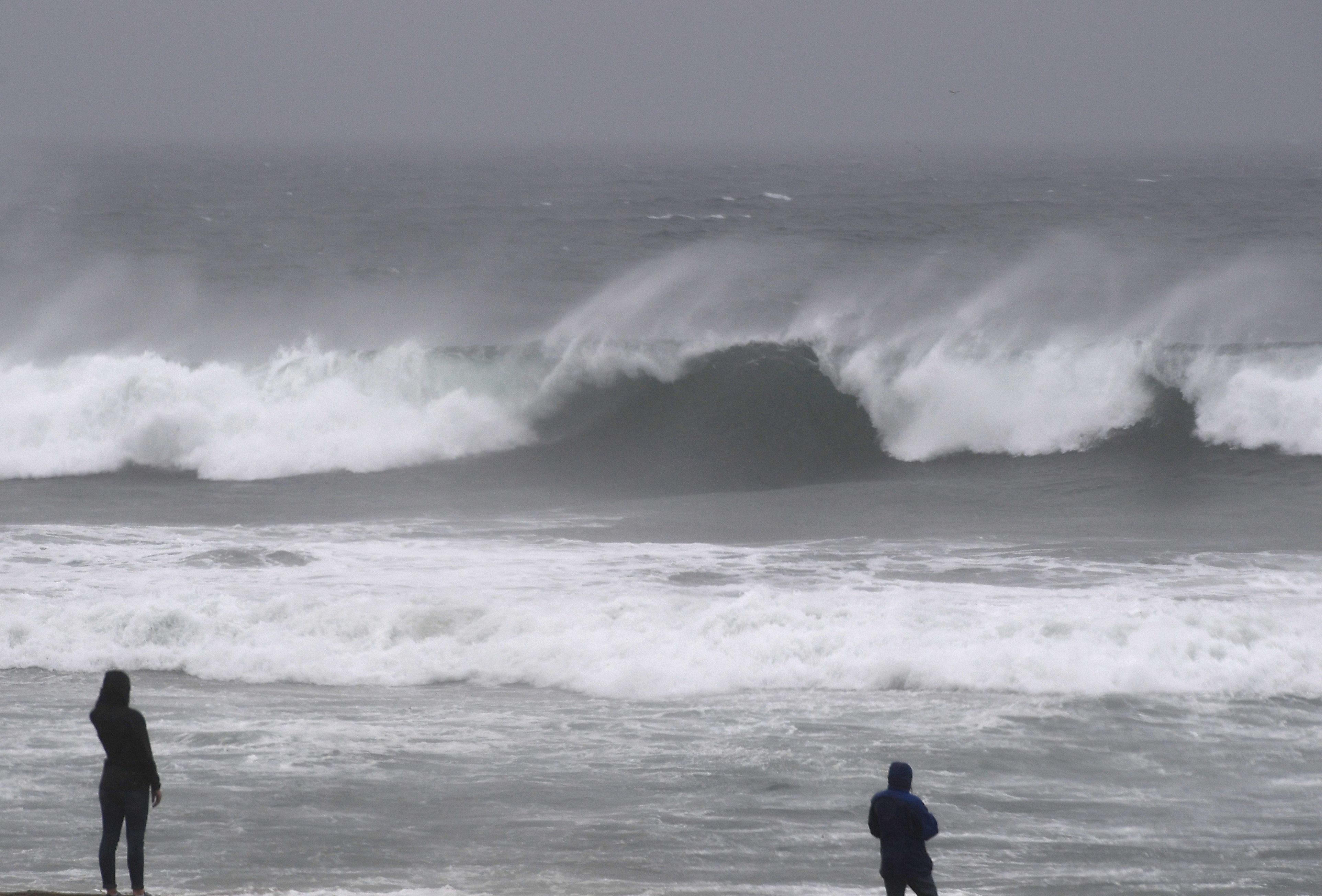 مواطنون أمريكيون يشاهدون الأمواج العالية على الشاطئ نتيجة العواصف