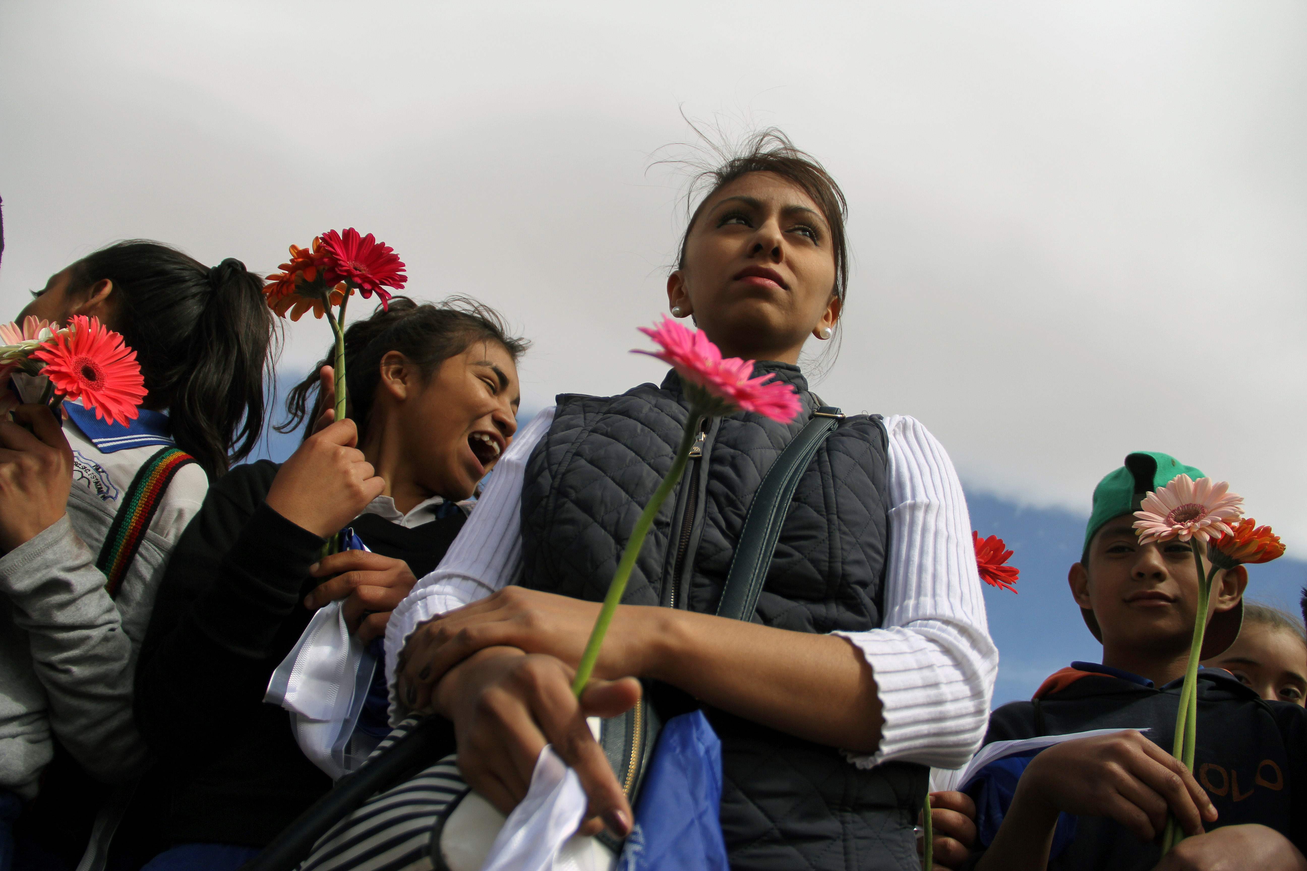 فتاة تحمل وردة وبجوارها اطفال يشاركون فى الوقفة الاحتجاجية ضد ترامب