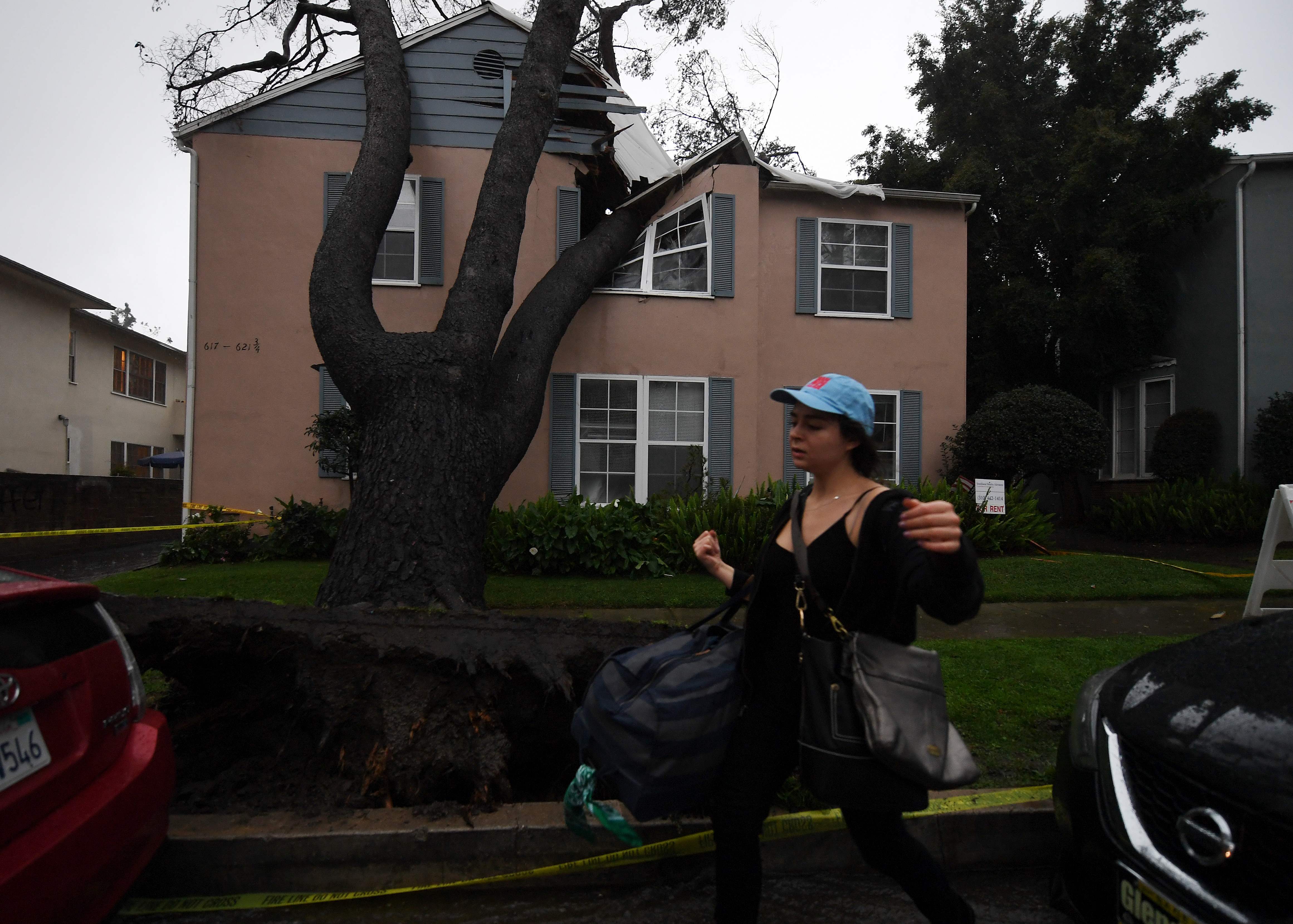 مواطنة أمريكية تغادر منزلها المتحطم أثر سقوط شجرة عليه عقب العاصفة