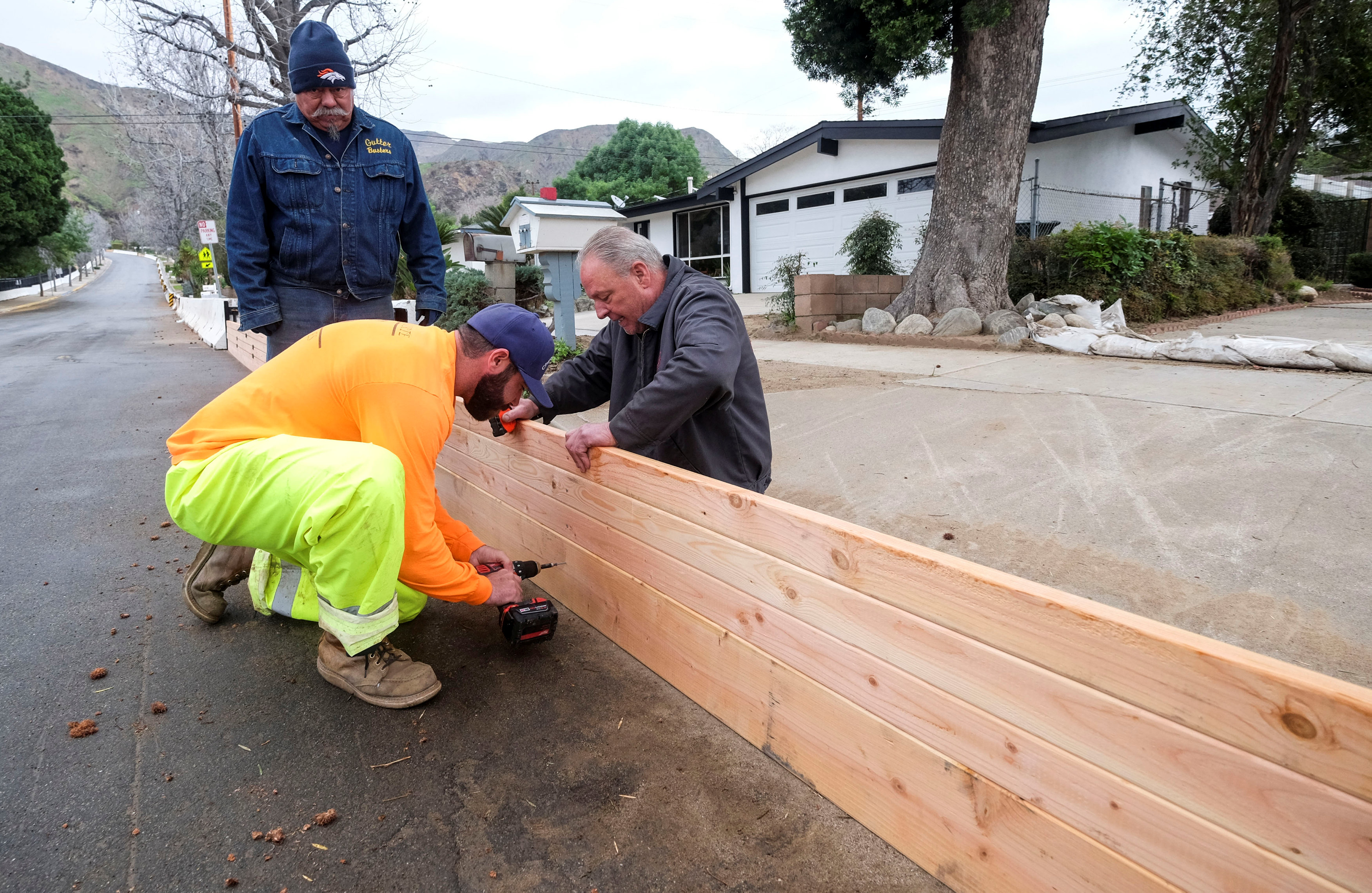 عمال يضعون ألواج الخشب على جنبات الطرق لمنع المياه من غمر المنازل