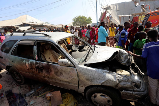 مدنيون يقفون بالقرب من السيارة المفخخة بعد انفجارها بسوق اداجير