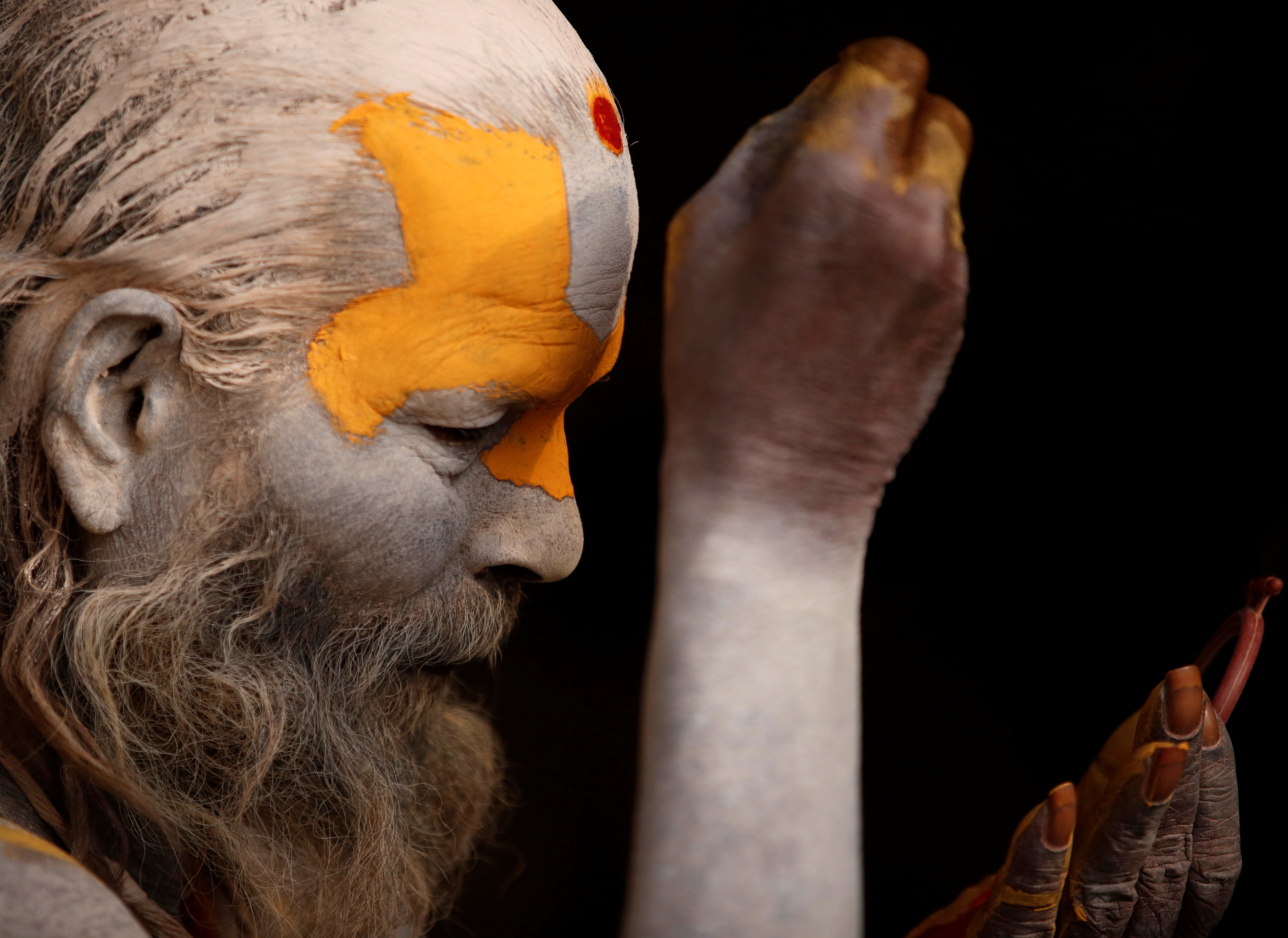 رجل هندوسى يلون وجهه بالألوان الزاهية استعدادًا للاحتفالات الدينية فى نيبال