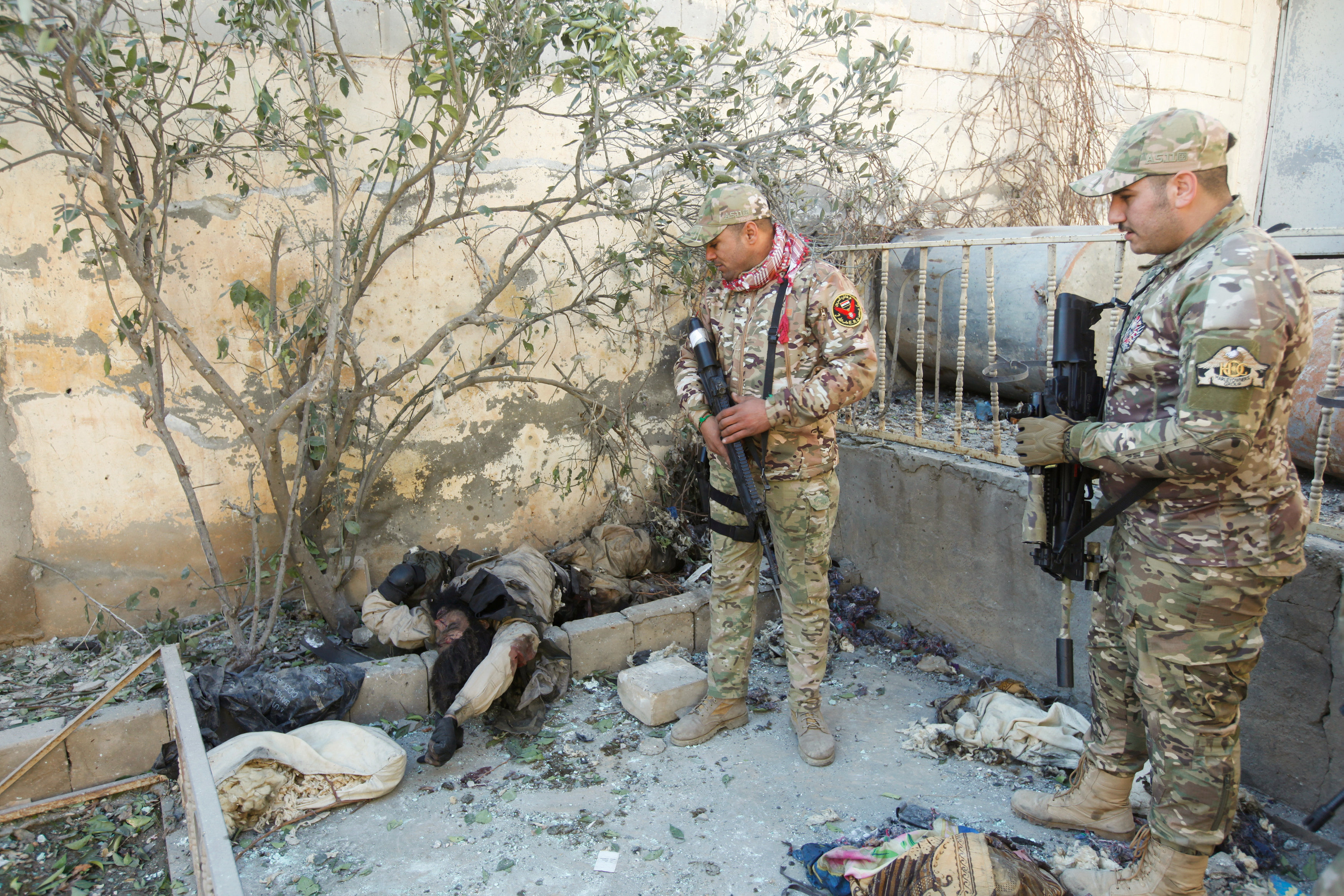 قوات الأمن العراقية تنظر لجثة داعشى قتل خلال اشتباكات بقرية البو سيف