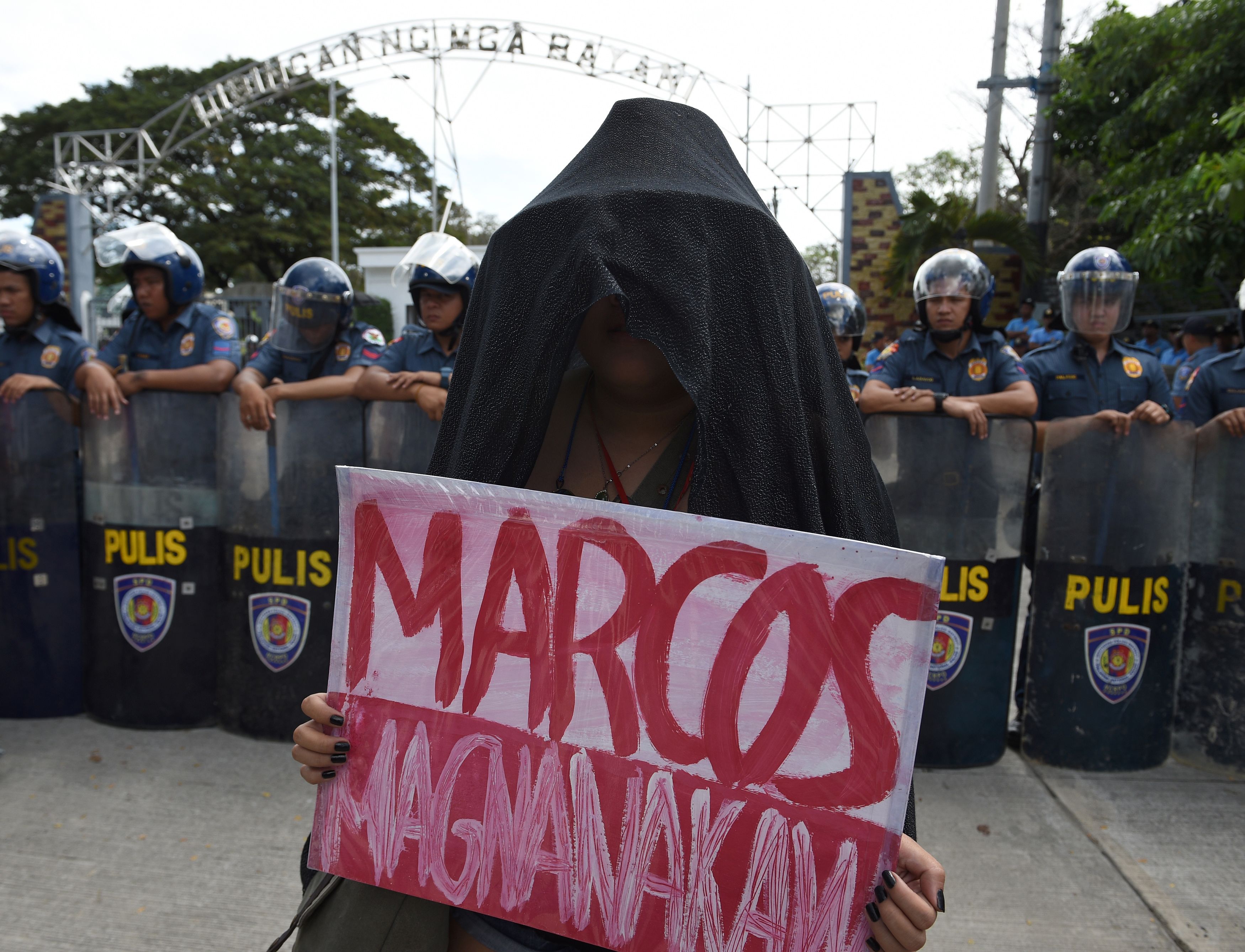 متظاهر يحمل لافته تهاجم الرئيس الفلبينى الأسبق فرديناندو ماركوس مكتوب عليها ماركوس اللص